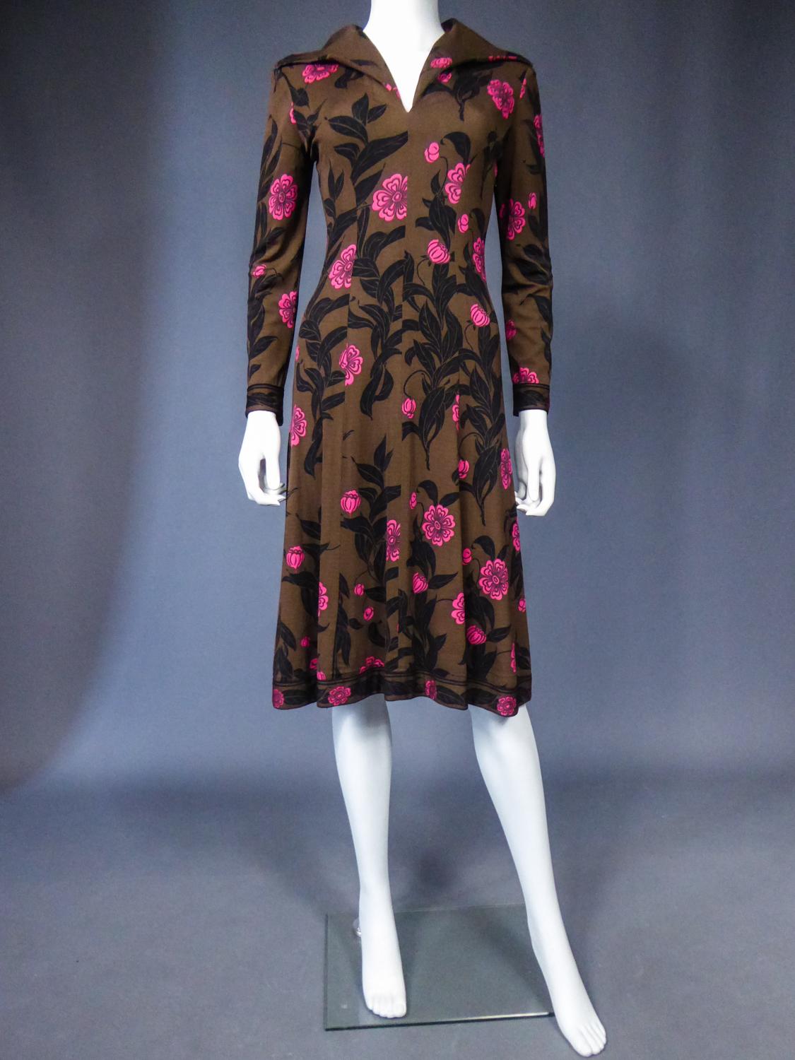 Circa 1975
Italy

Mid-season Emilio Pucci dress in brown silk jersey printed with pink flowers and black leaves from the 1970s. Low-necked skin-tight dress with wide collar widening from the waist for a fluid skirt. Long sleeves ending in the same