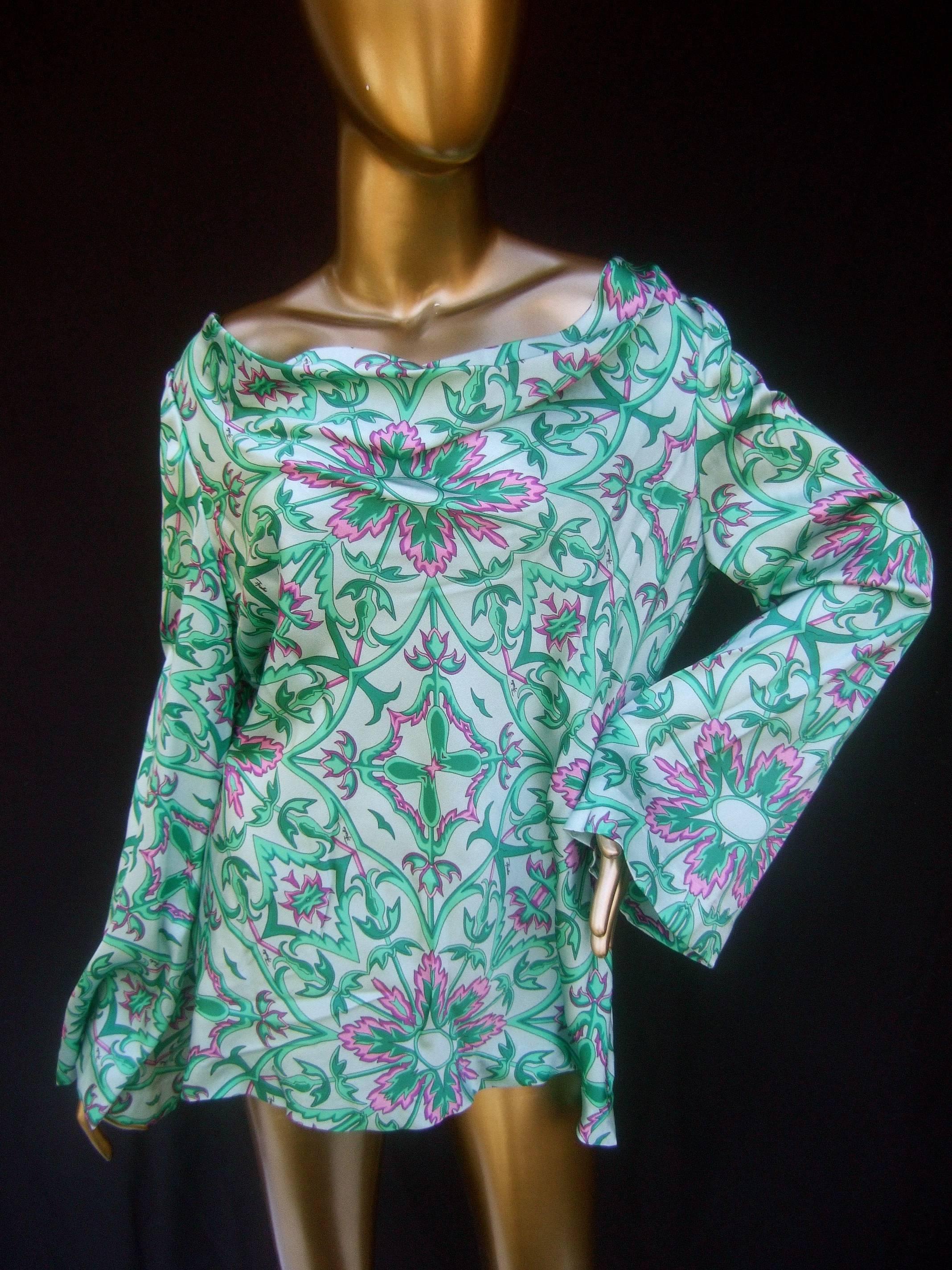 Emilio Pucci floral print tunic style blouse c 1970s
The unique tunic graphic print blouse is illustrated with a field
of pink flowers combined with sinuous leafy foliage 
set against a pale mint green silky satin background 

Emilio's script name