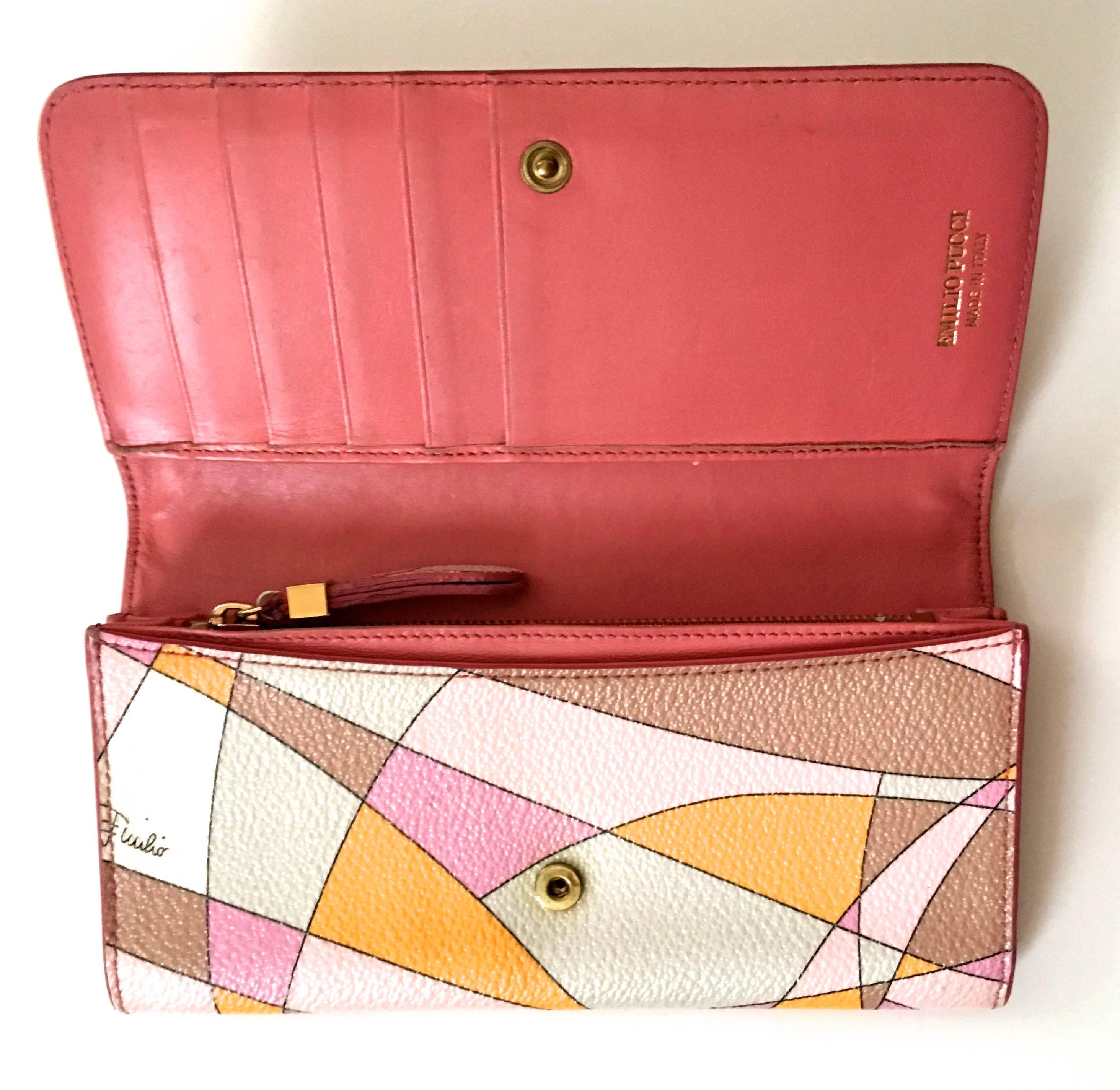Presented here is a leather wallet from Emilio Pucci. This lovely wallet is made of 100% leather throughout. On the exterior of the wallet, there is a geometric design in colors of pink, white, orange, beige and tan. The wallet opens to reveal solid