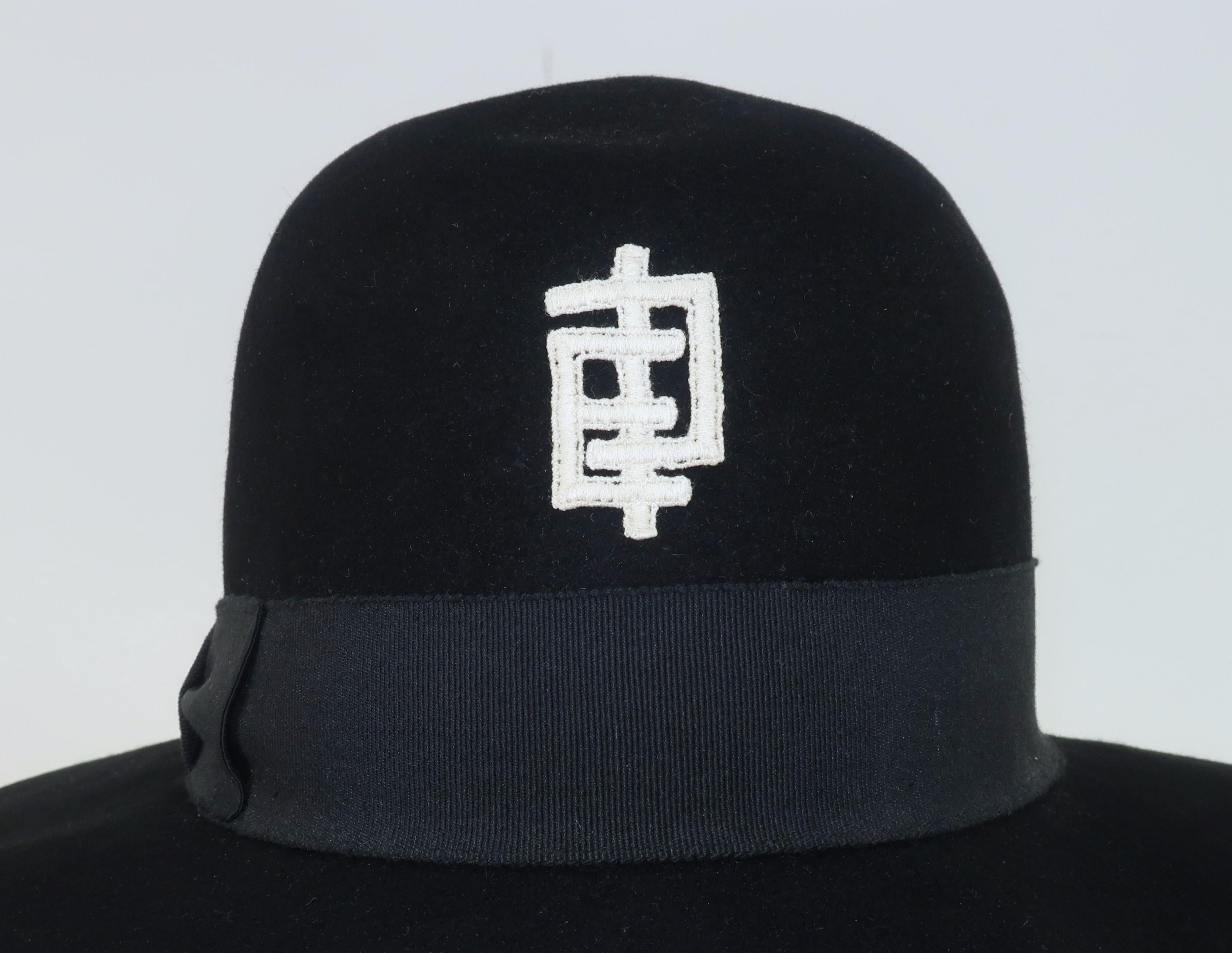 1960's Emilio Pucci floppy wide brim black wool felt hat with natural white stylized 'EP' logo at the crown. The brim sports a classic grosgrain band.  The chic floppy style is perfect for sun shade or traveling incognito. Labelled to the interior