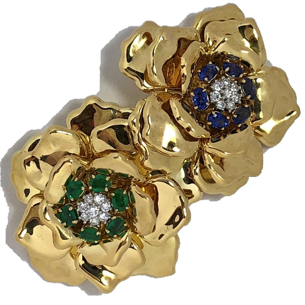 Made by Emis Beros, this outstanding, double flower brooch is set with six faceted, oval shaped, bright green emeralds surrounding eight round brilliant cut diamonds, and with six faceted, oval shaped bright blue sapphires surrounding eight round