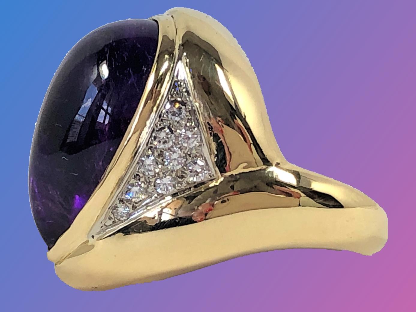 Made by Emis Beros, this large scale gold ring is set with one center 8.5CT
Pear Shaped Cabochon Amethyst flanked by 18 round brilliant cut diamonds weighing an approximate total of .65CT of overall G Color and VS1 Clarity. Measuring 1 1/16 inch