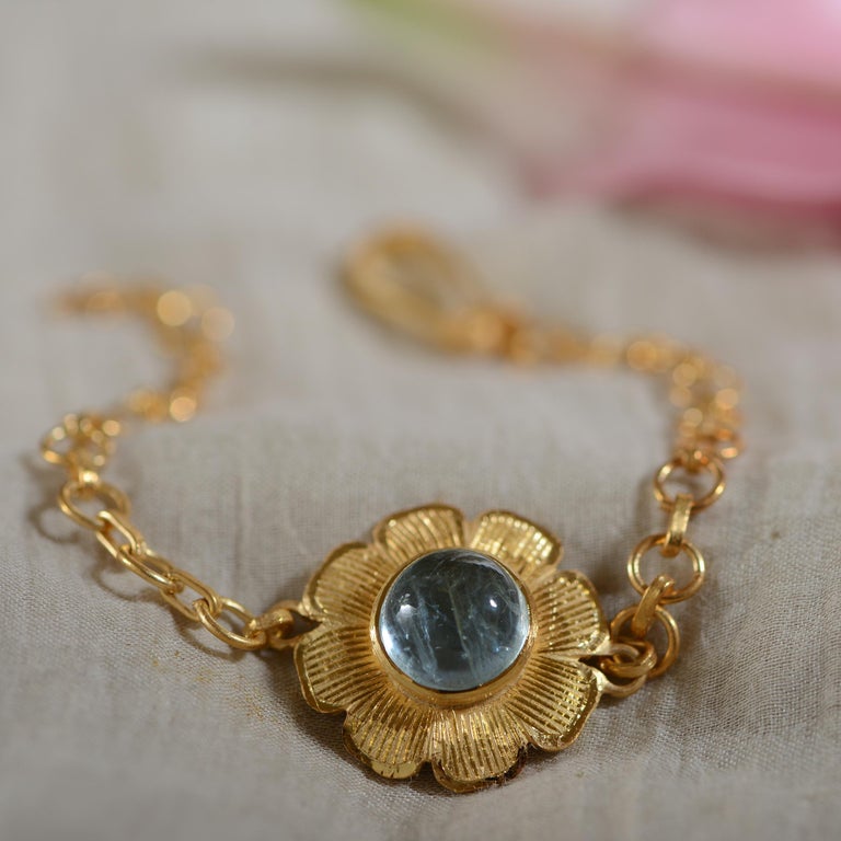 

The Aquamarine Gold Plate Bracelet is handmade and adjustable. It has a beautiful central cabochon aquamarine, surrounded by hand engraving work. The bracelet is made in sterling silver coated with 24kt gold vermeil. It has a matching ring and