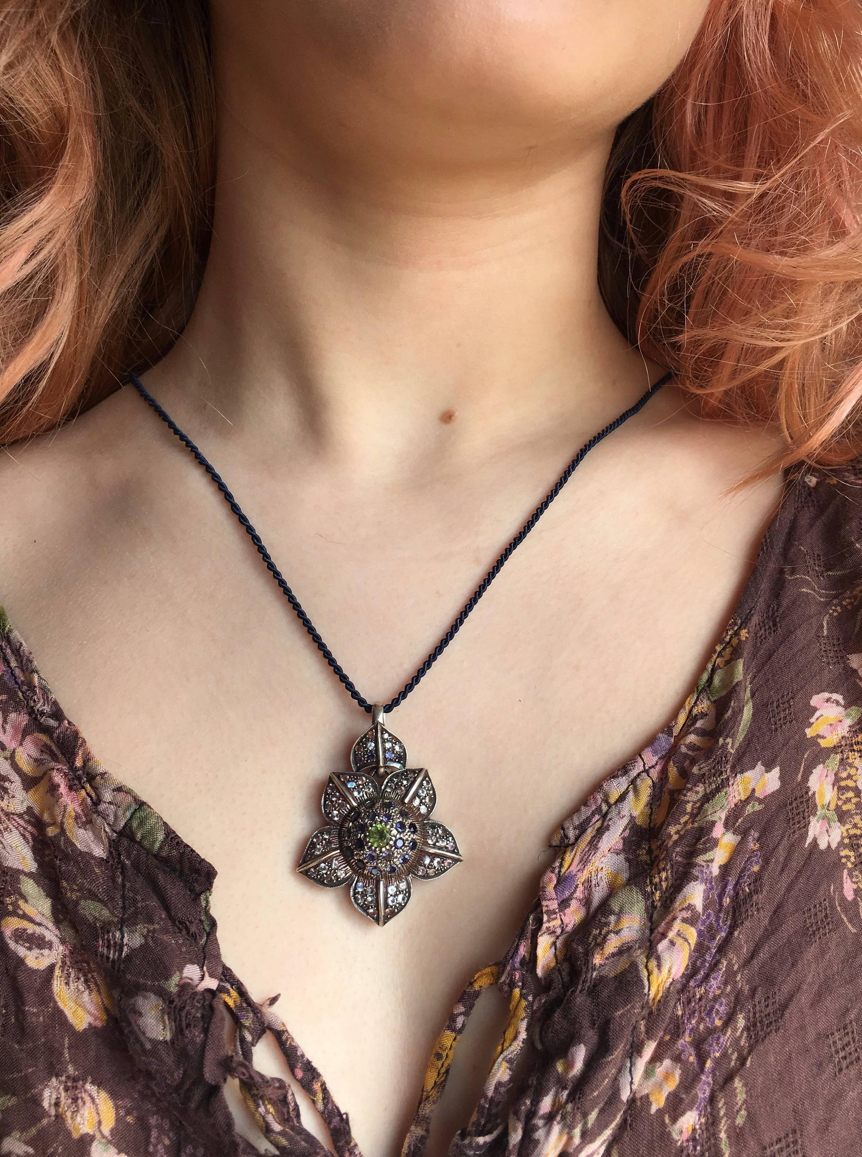 This  exquisite  Moonstone Peridot Iolite Flower Pendant is one of a kind.  Handmade in our workshops,  it features iolites and rainbow moonstones embedded in its petals, with vibrant green peridot in the centre.  It also has hand carving work on it