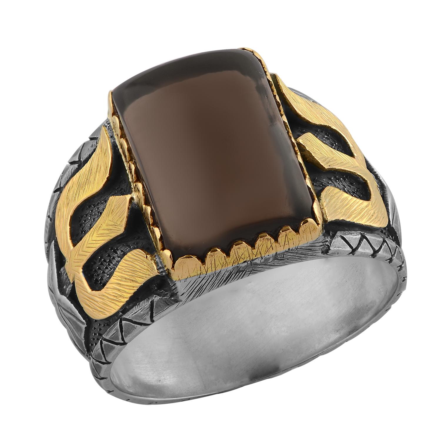 This statement men's ring has been handmade in our workshops. It features a central smokey topaz gemstones, which is set in 18k gold. The ring band is made of oxidized sterling silver, which has been hand engraved, and overlaid with 18k gold