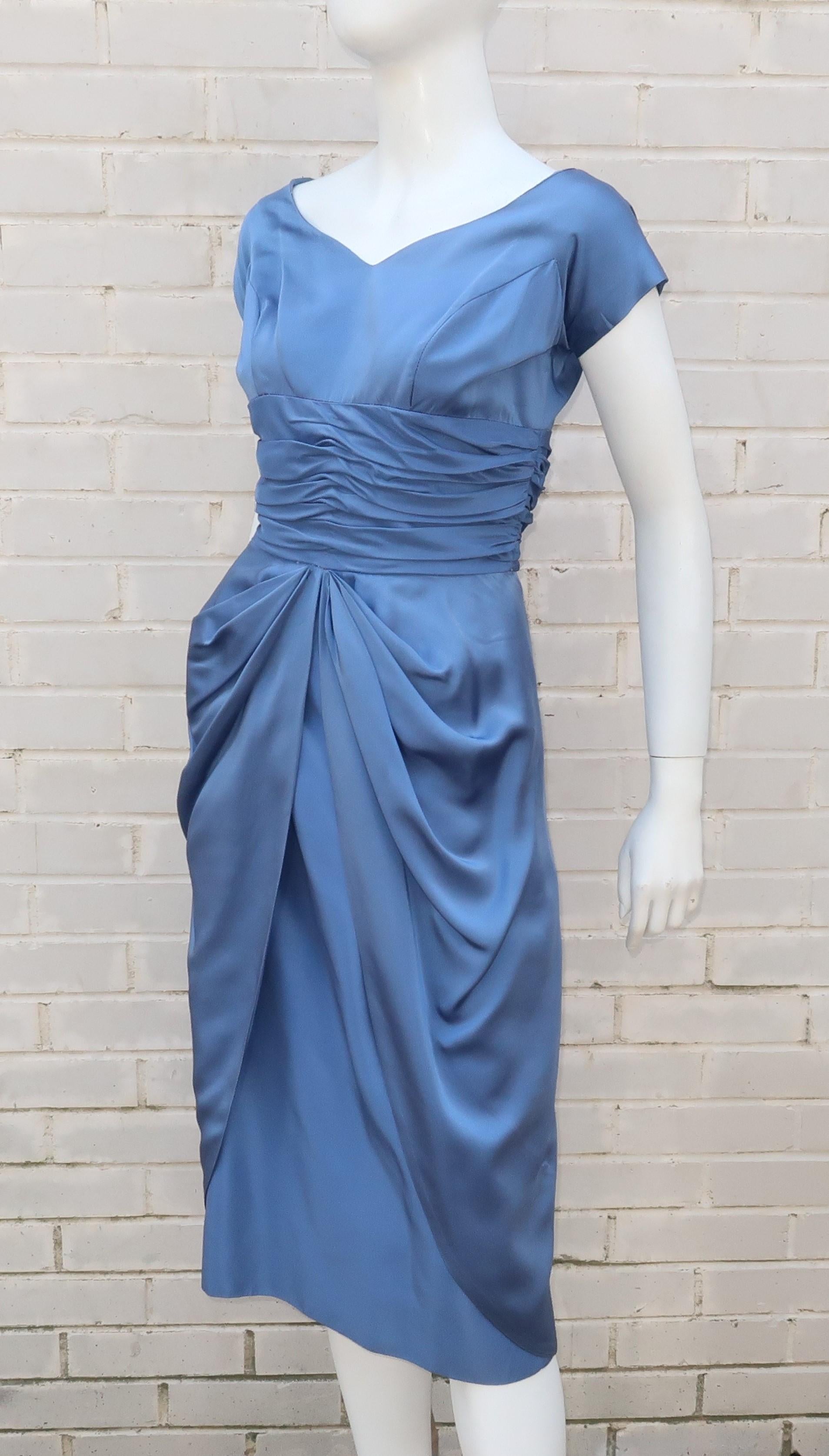Emma Domb is the bomb!  This 1950’s bombshell dress is worthy of an houglass figure and a stylish cocktail party.  The icy periwinkle blue satin fabric is a beautiful backdrop for the ballerina style neckline and ruched empire waist accented with a