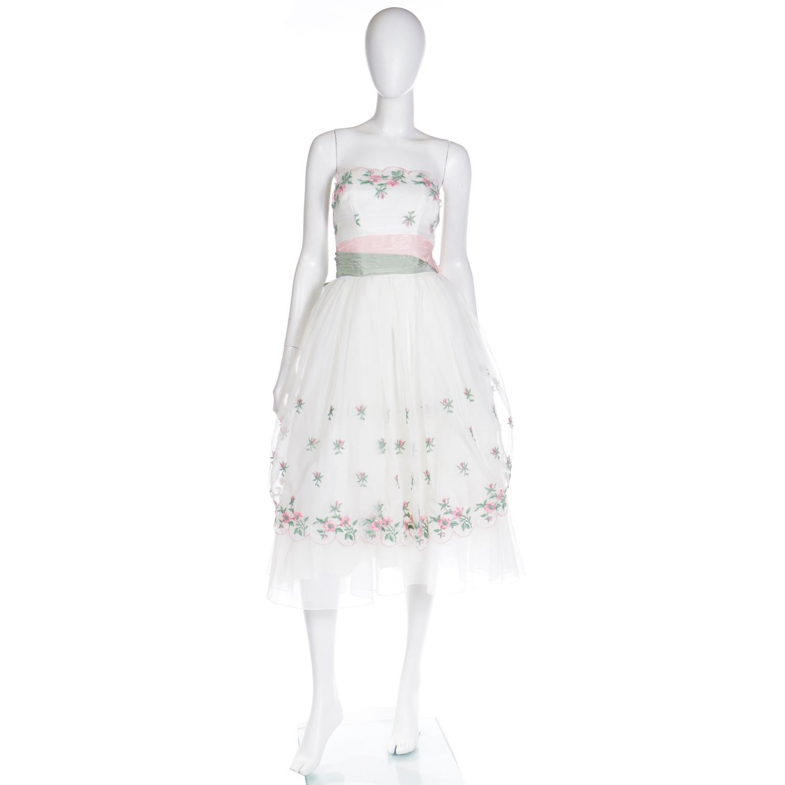This magical vintage 1950's Emma Domb strapless party dress is in a princess cut with a full skirt. The dress is embroidered with pretty pink flowers with green leaves on the bodice and the top layer of the skirt portion. This dress has a double