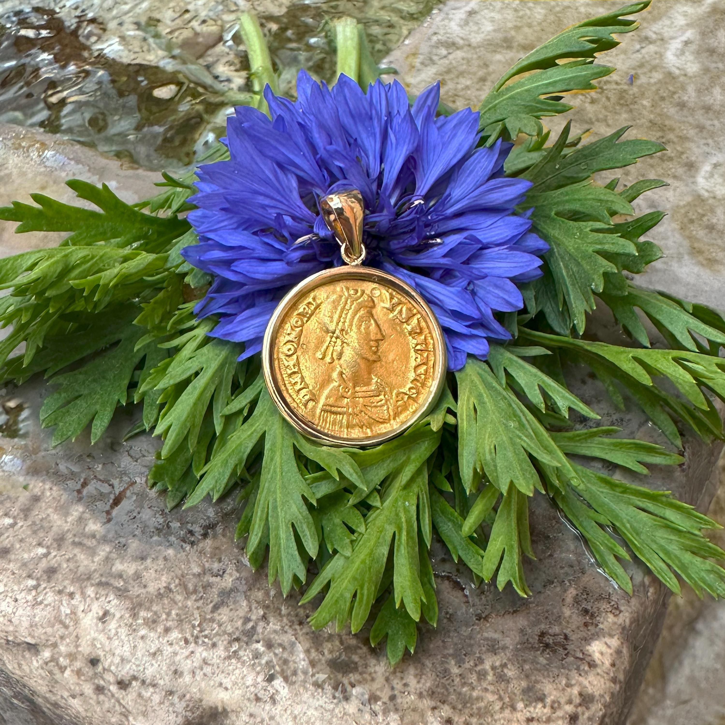 Questo ciondolo mostra un autentico solidus romano 24 Kt del regno dell'imperatore Eleg (393-423 ADS), incastonato in un'elegante cornice d'oro 18 Kt.

Il fronte della moneta presenta un ritratto dettagliato di Onorio, che indossa un diadema, un
