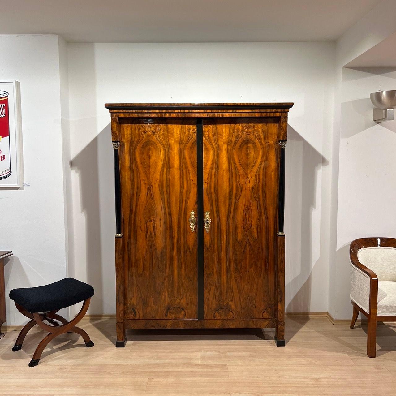 Elegant large Empire or early Biedermeier armoire with original brass hardware and gorgeous walnut veneer.
The armoire has a beautiful book-matched walnut veneer and is shellac hand-polished (French Polish). The doors inside are counter veneered in