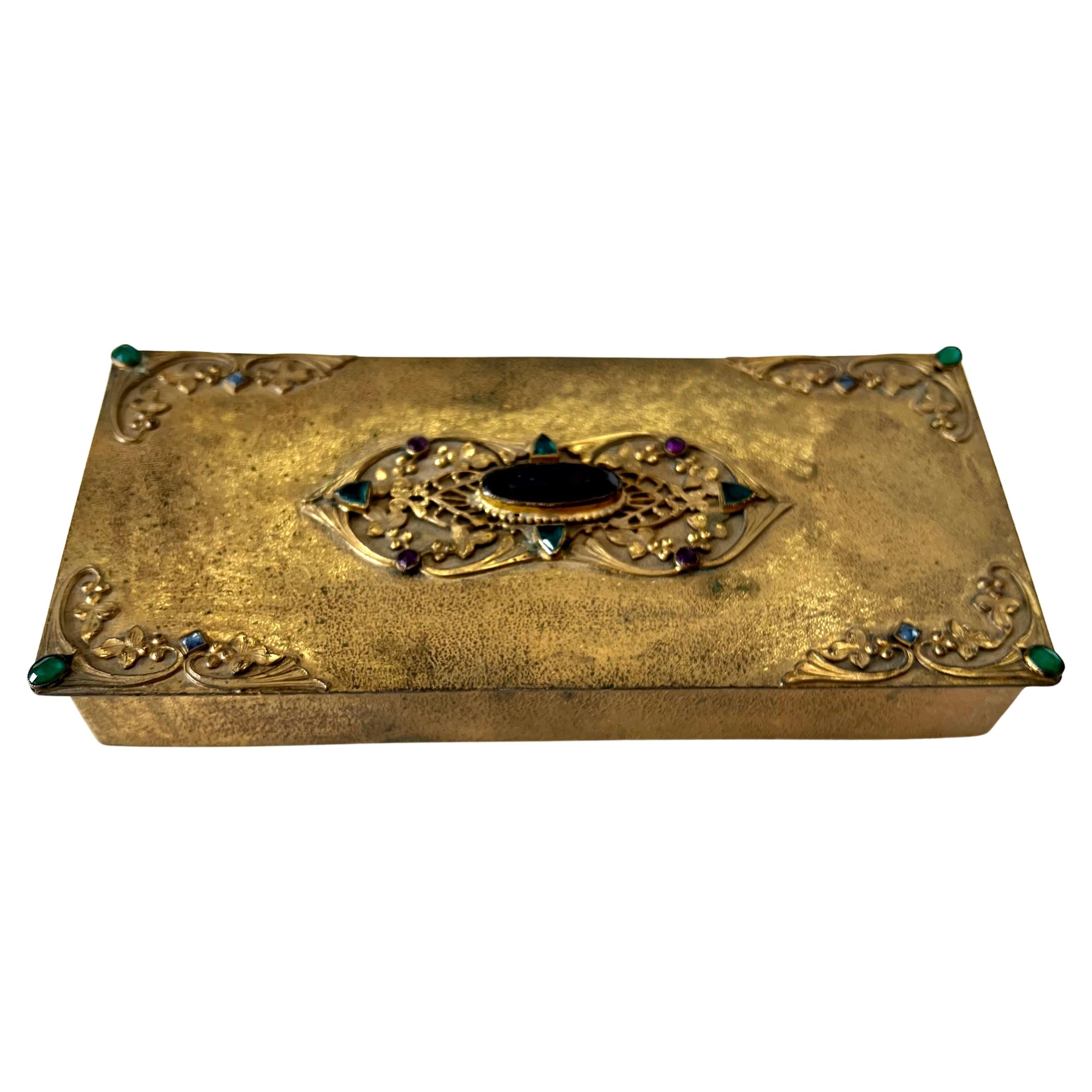 A wonderful box of art gold, with detailed corners and centerpiece, all with stones.  All Stones are in tact with no chips or fractures.  The box is lidded with a hinge and has an interior wooden piece.  

A compliment to any vanity, cocktail table,