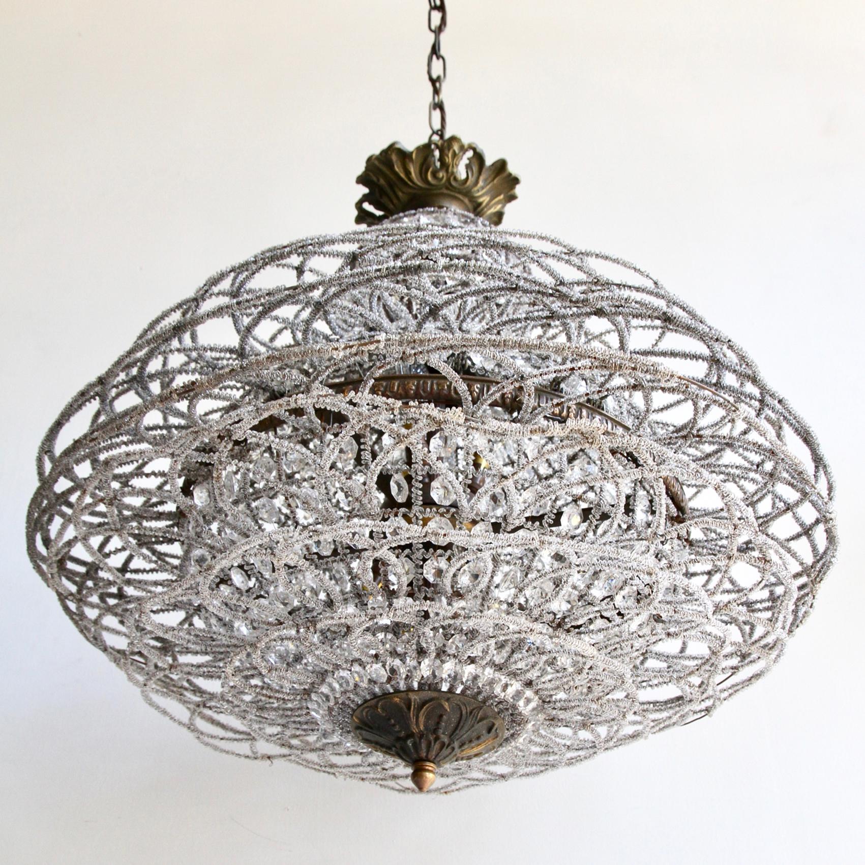 This charming French globe chandelier is in the style of the Montgolfier Balloon chandeliers types with outer rings. The framework is wrapped in glass beads and encased with glass buttons. The lamps are positioned so that when it is lit there is an