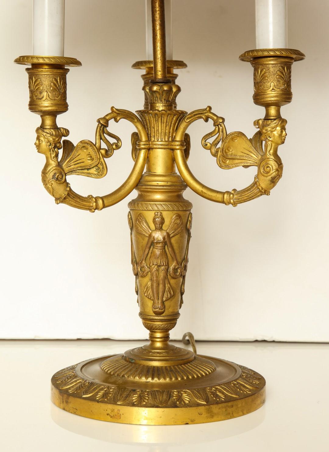A French Empire bouilotte lamp, stylized finial and caryatid candle arms, first half of the 19th century.