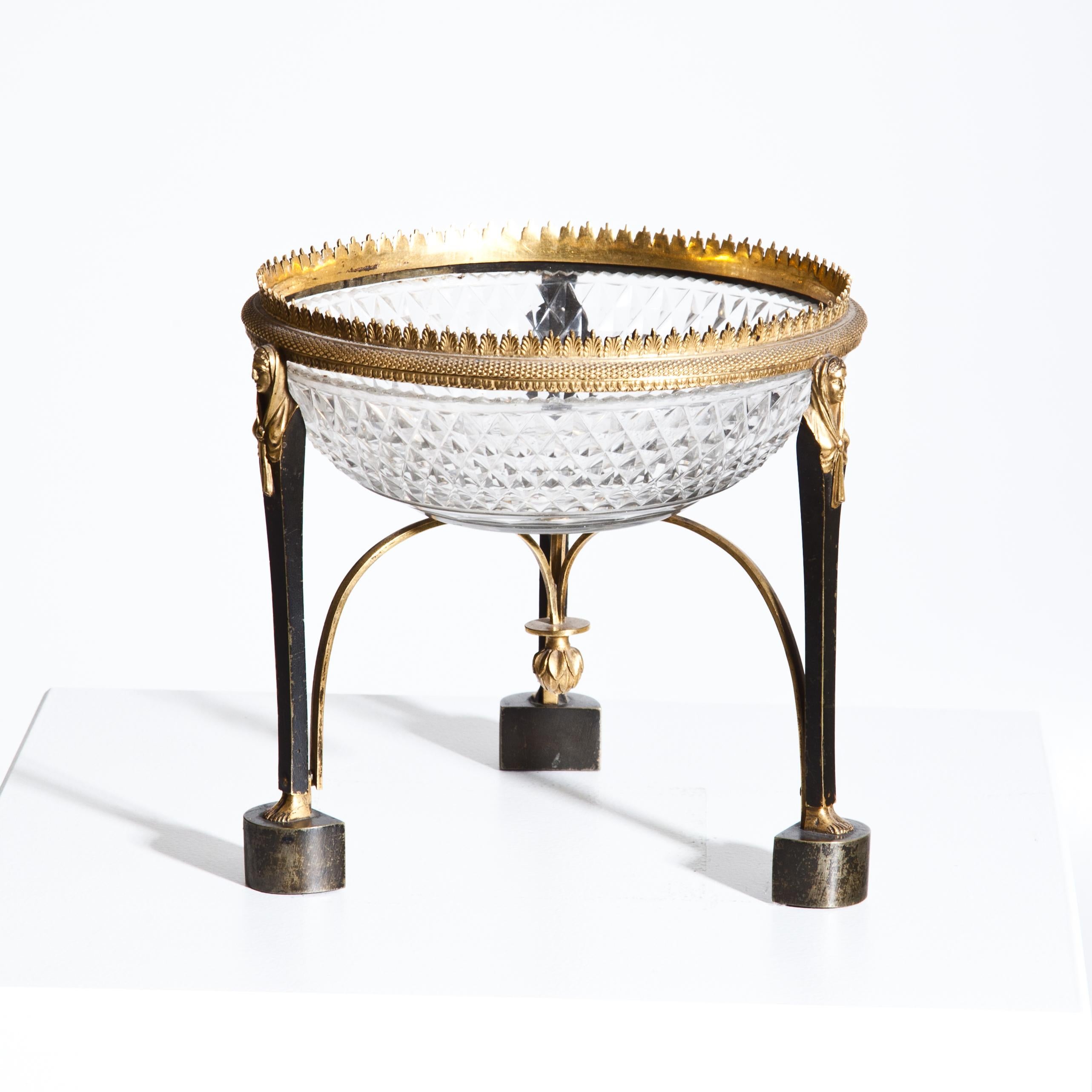 Round Empire glass bowl with diamond-cut wall and fire-gilded bronze mounting. The bowl is supported by three caryatids and stabilized by gilded arches with one artichoke-shaped cone.