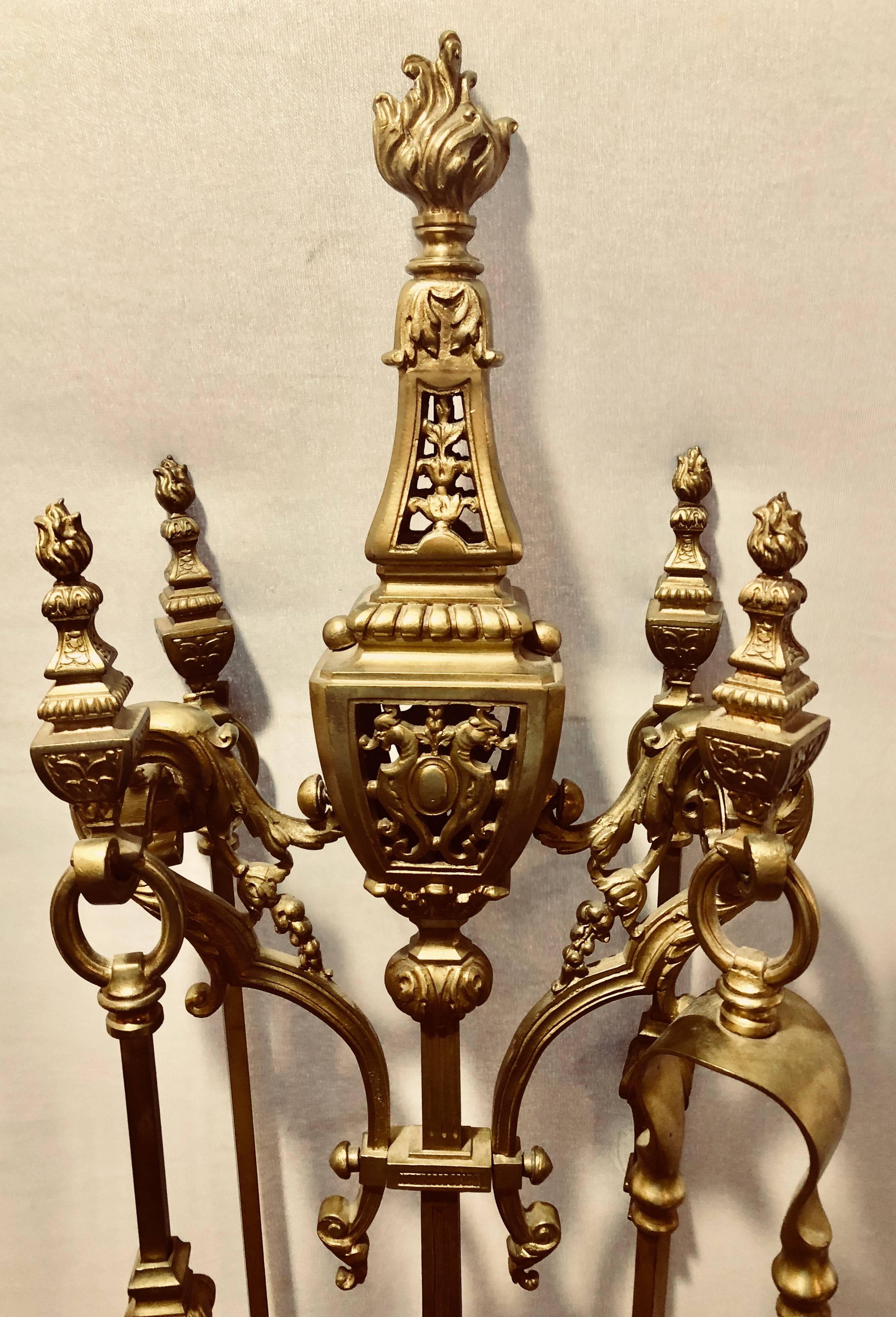 An Empire brass fireplace tool set having four tools and a stand to keep everything in place. The whole made of heavy solid brass or bronze.