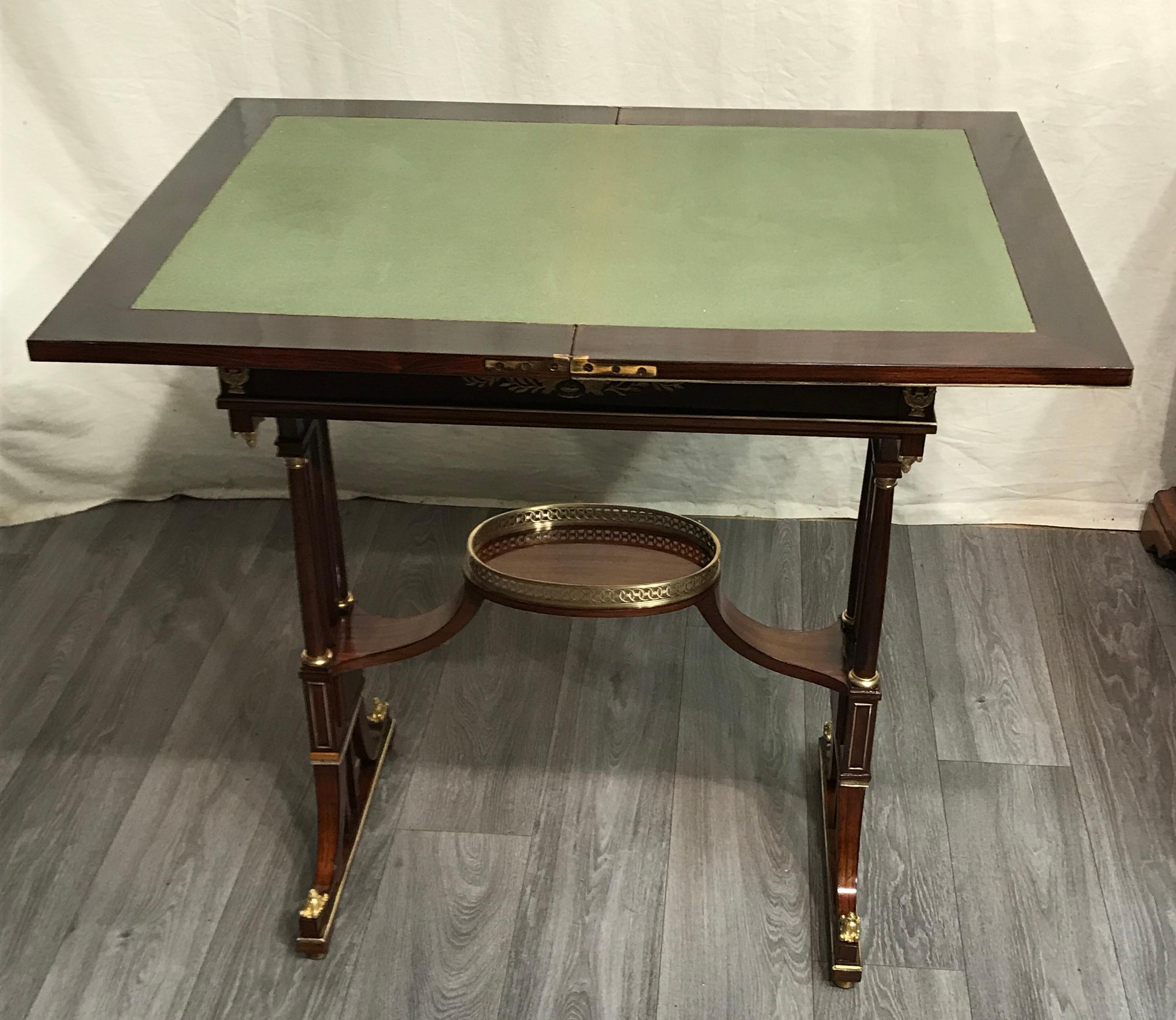 This unique card or tea table dates back to around 1880-1900 and comes from Vienna. It has an elegant mahogany veneer and gorgeous bronze fittings. The small table has a fold out top. The center of the unfolded top is covered with green leather. The