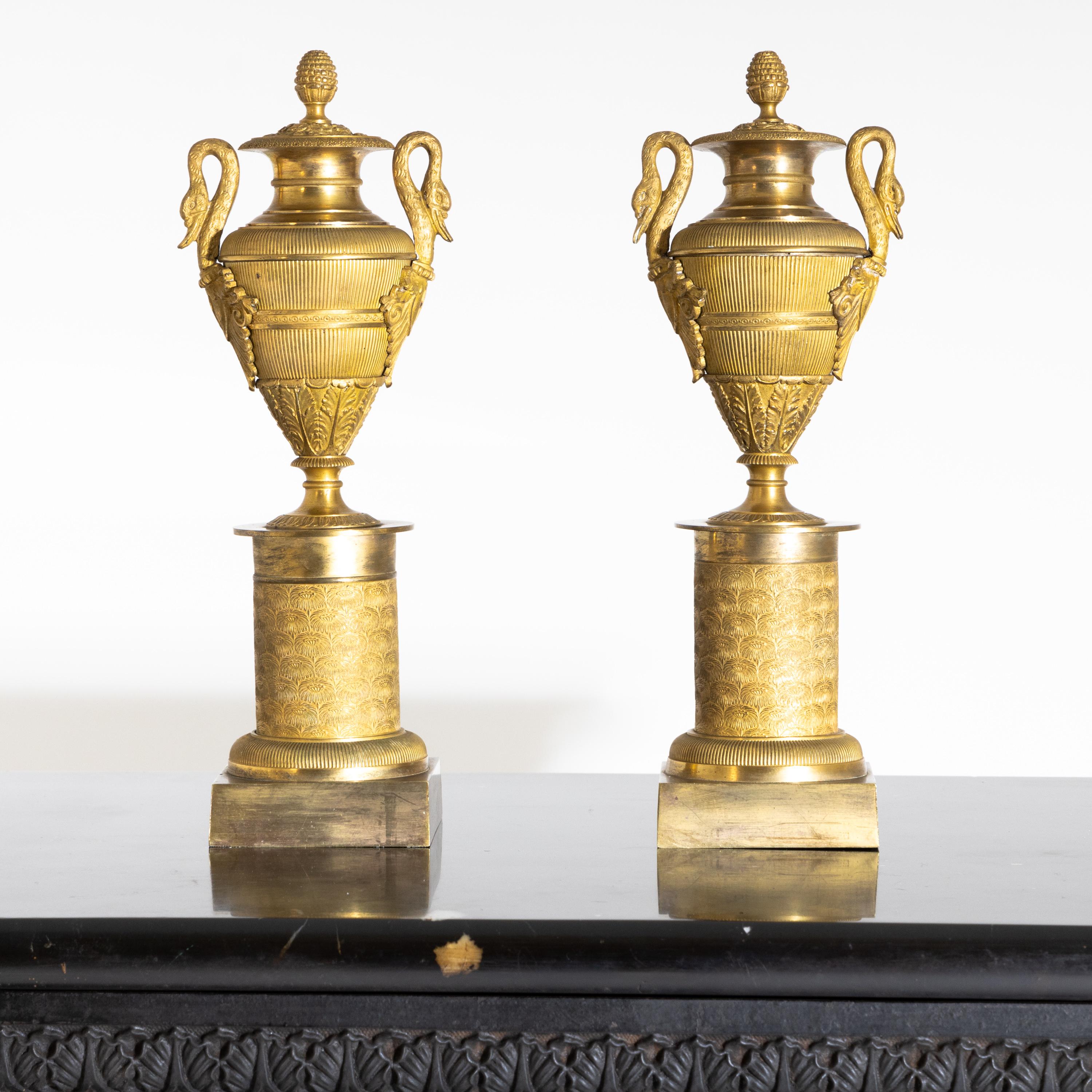Pair of Empire cassolettes in urn form with swan neck handles on cylindrical bases. Fire-gilt bronze.
