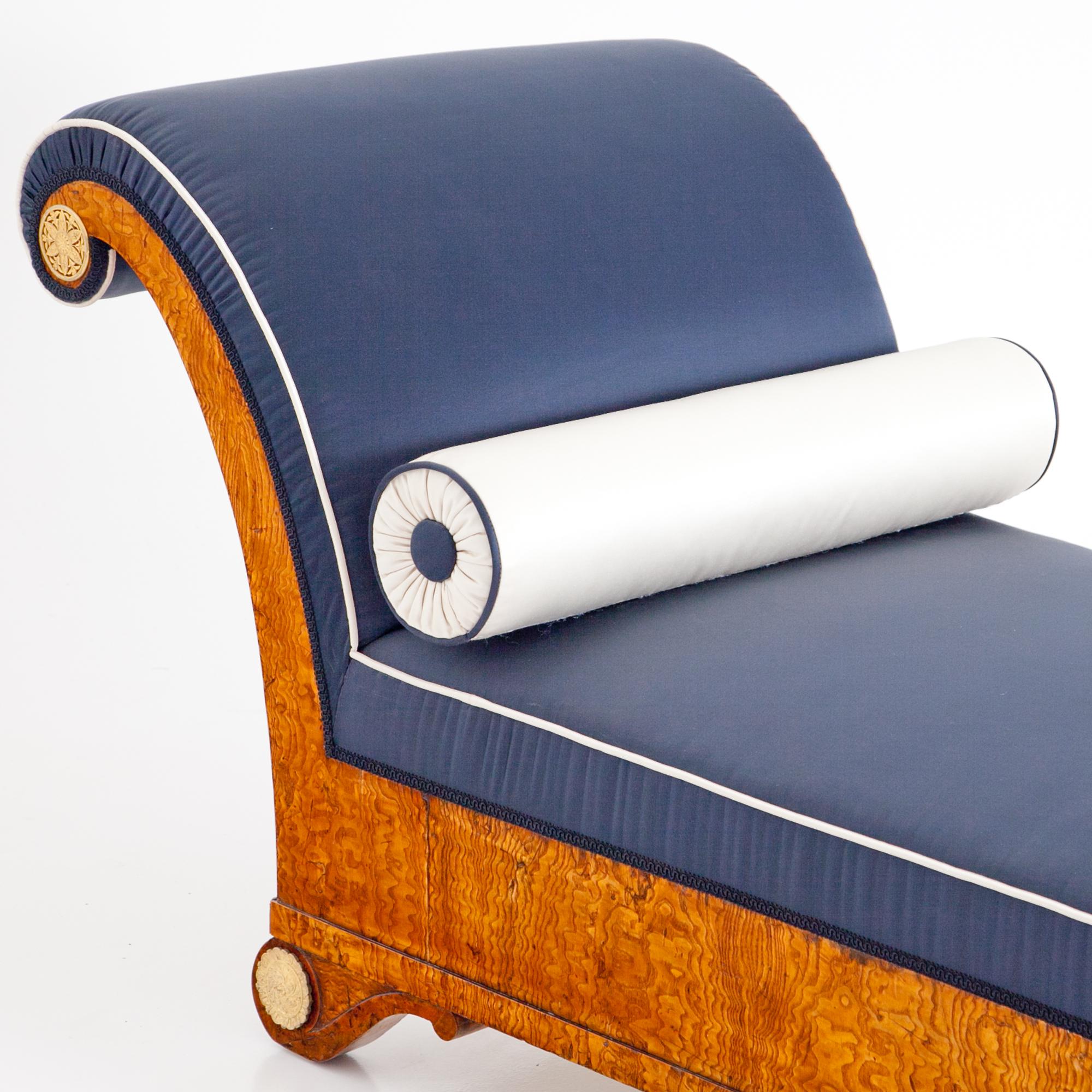 Empire Recamiere in ash-tree veneered with fire gilt bronze rosettes on the curved backrest and feet. The length of the bed is 155 cm, the seat height 40 cm. The Recamiere was completely reupholstered with a dark blue fabric with white piping. The