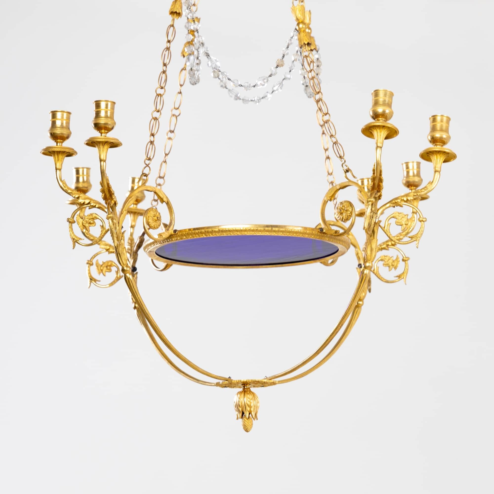 Large eight-flame chandelier of the Russian Empire with cobalt blue glass and fire-gilded arms with cockerel decoration and hanging pine cone. The supporting hoop is connected by four link chains to the ceiling crown, which consists of a glass dome