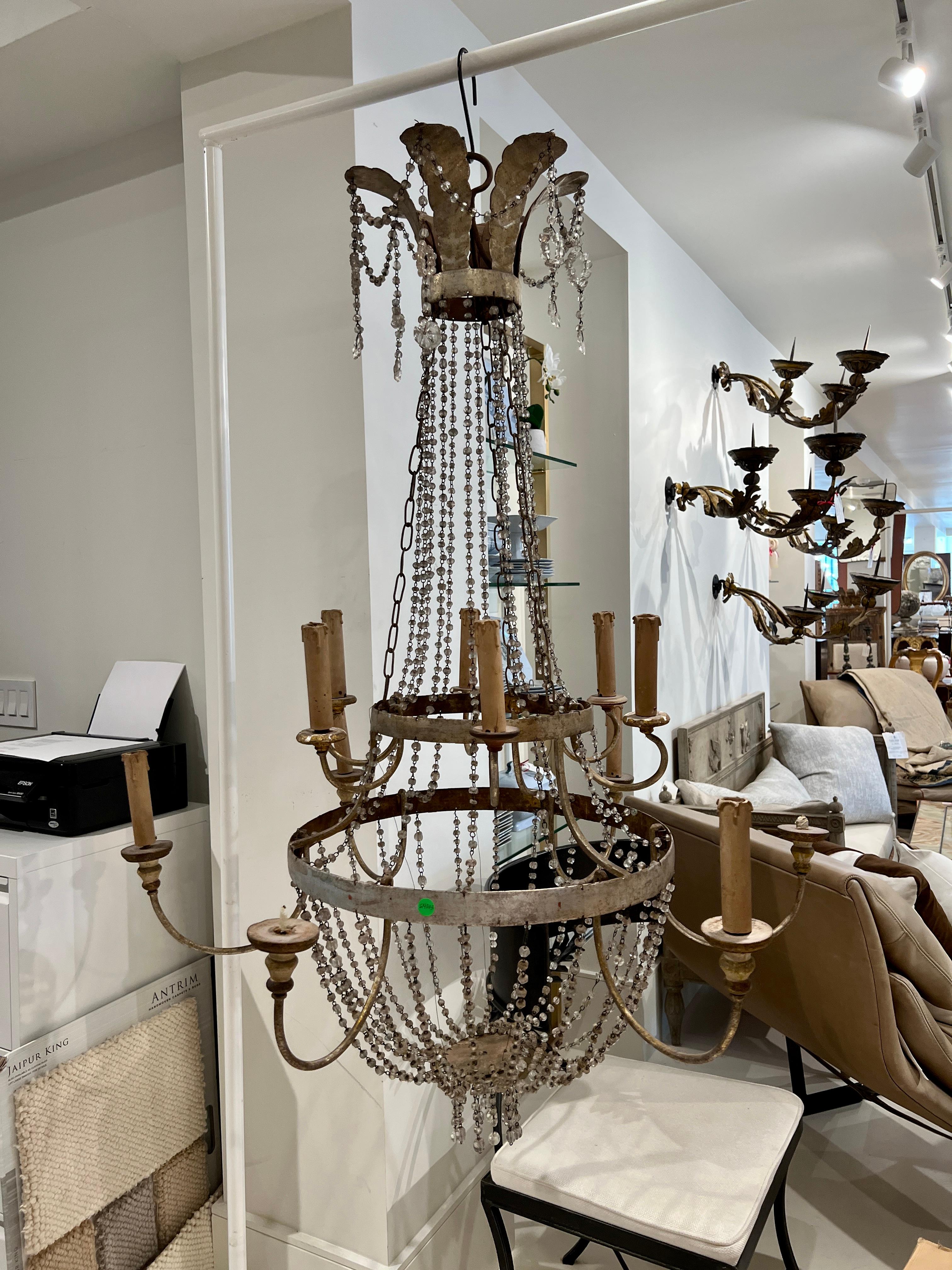 Impressive in scale and style, this Empire chandelier is crowned with acanthus leaves dangling crystal drops. The two silver banded tiers support the 12 arms with the crystal beaded basket dripping with more crystals at the bottom. An elegant