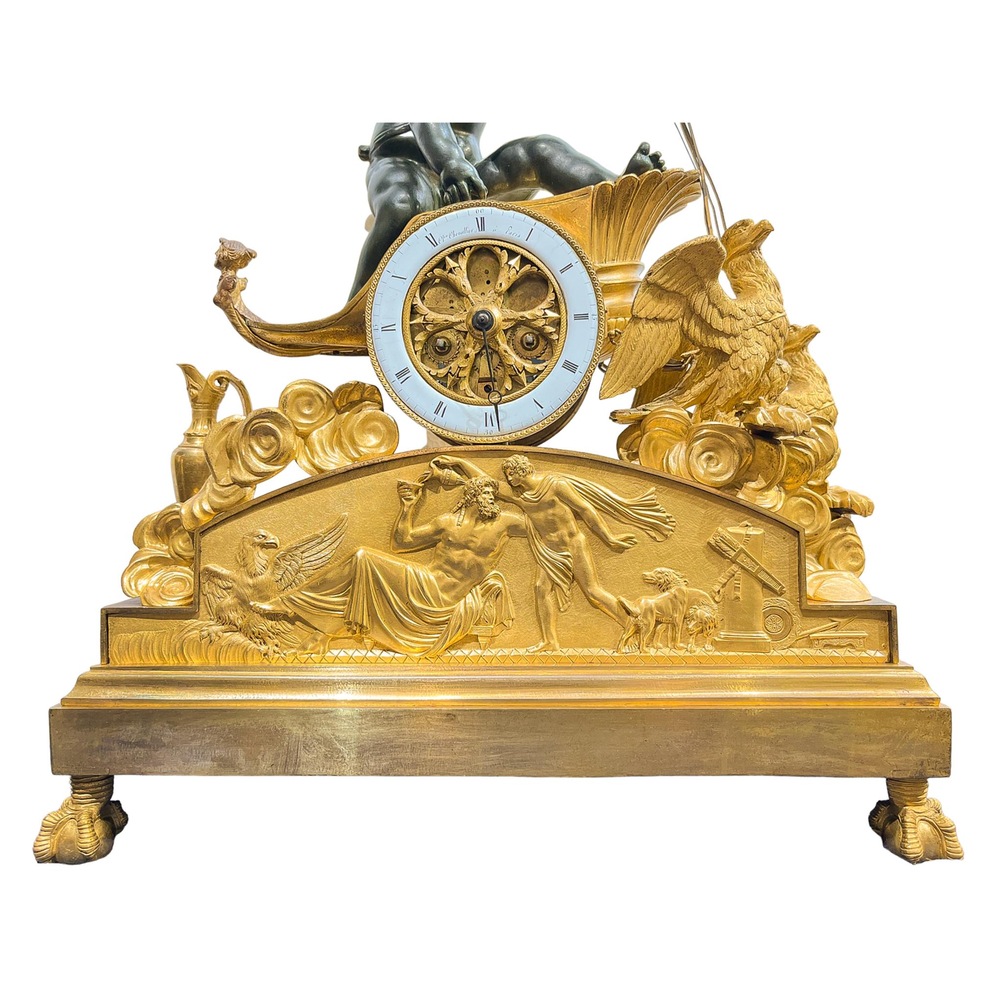 Fascinating gilt bronze Empire chariot clock surmounted by a bronze putto in Zeus’ chariot, drawn by two eagles through the clouds. On the left side we see a classical ewer with snake shaped handle. The scene rests on a base with a bas-relief
