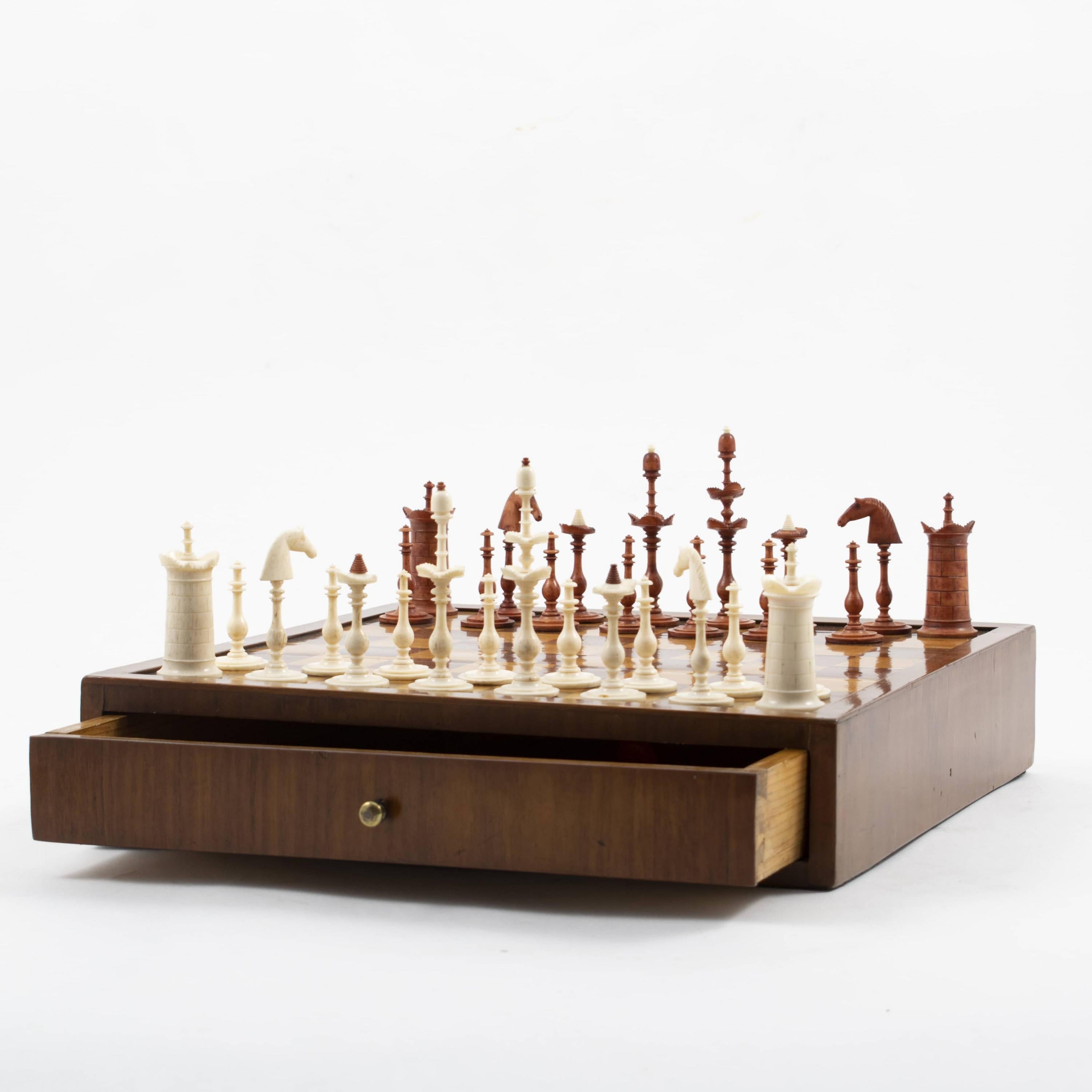 Early 19th century Empire mahogany chess set with drawer.
Checkerboard with inlaid squares of mahogany and satinwood.
The chess set is complete with 32 original hand-carved pieces, red and white.
Copenhagen, Denmark 1810.

Height with the