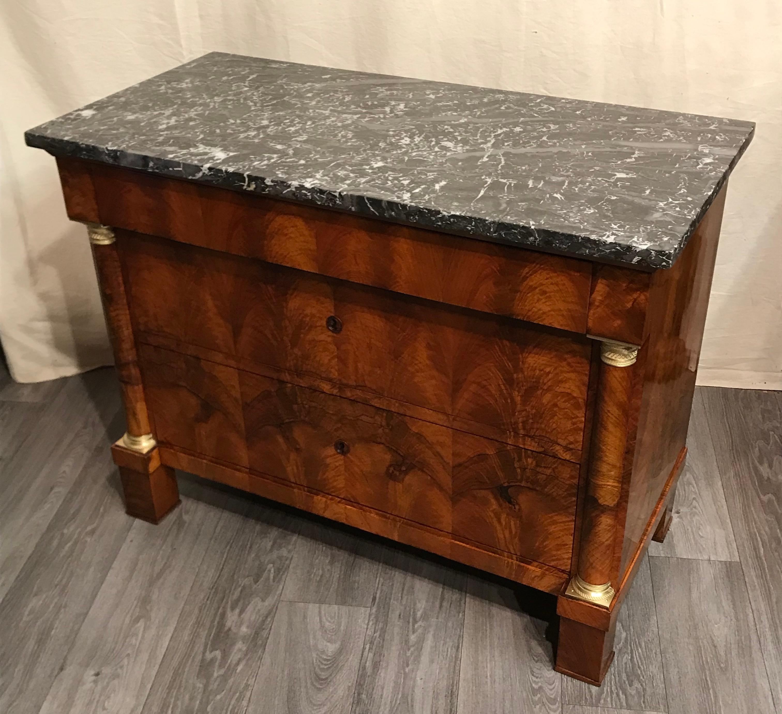 This elegant Empire chest of drawers comes from France and dates back to 1810. The three drawer commode has a very pretty walnut veneer and a marble top. The original ebonized wooden escutcheons do not distract from the beautiful veneer grain. The