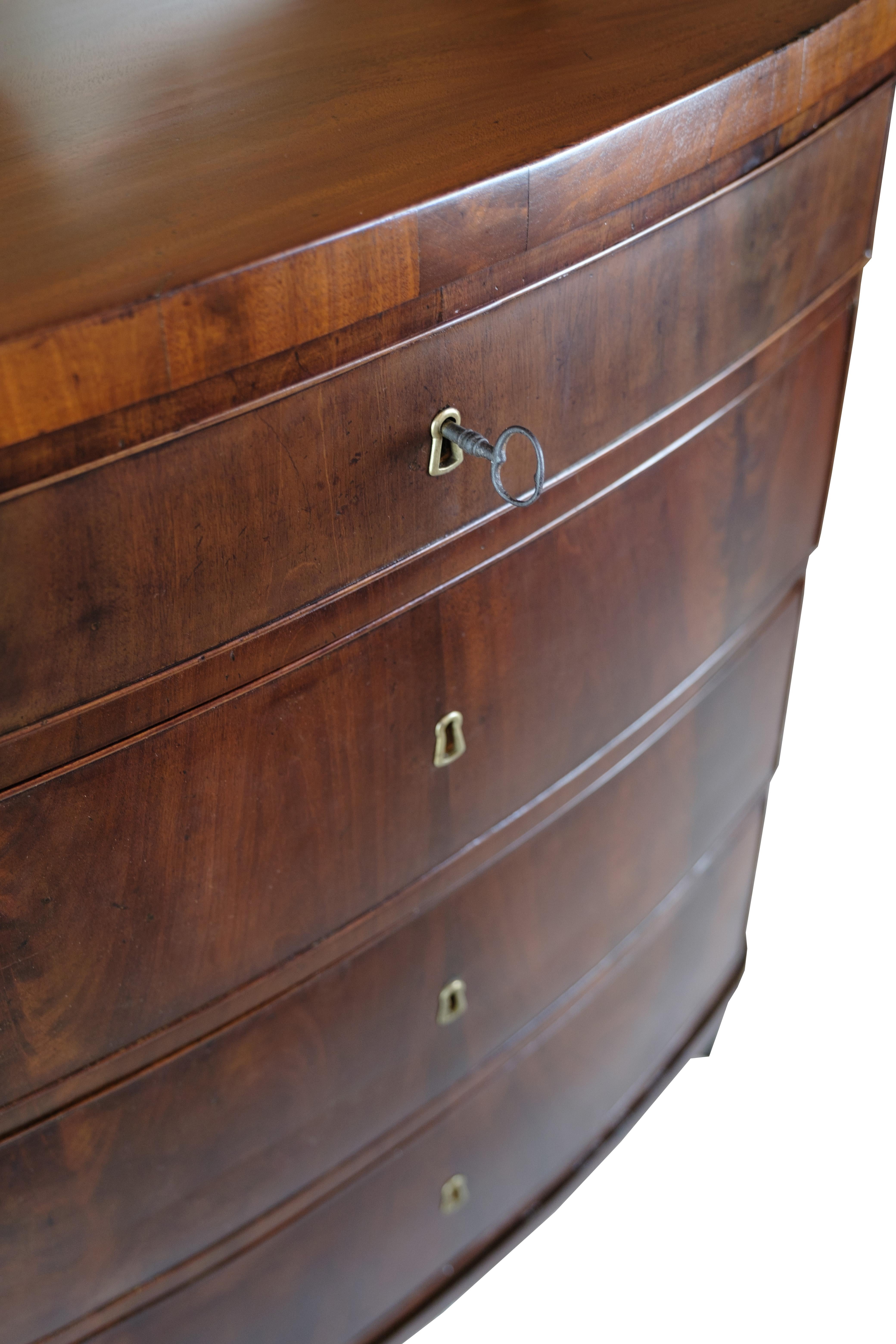 An Empire chest of drawers in polished mahogany with a curved front from around the 1820s is a fantastic example of classic and elegant furniture design from the early 1800s.

Mahogany wood is an exclusive wood with a rich and deep color that gives