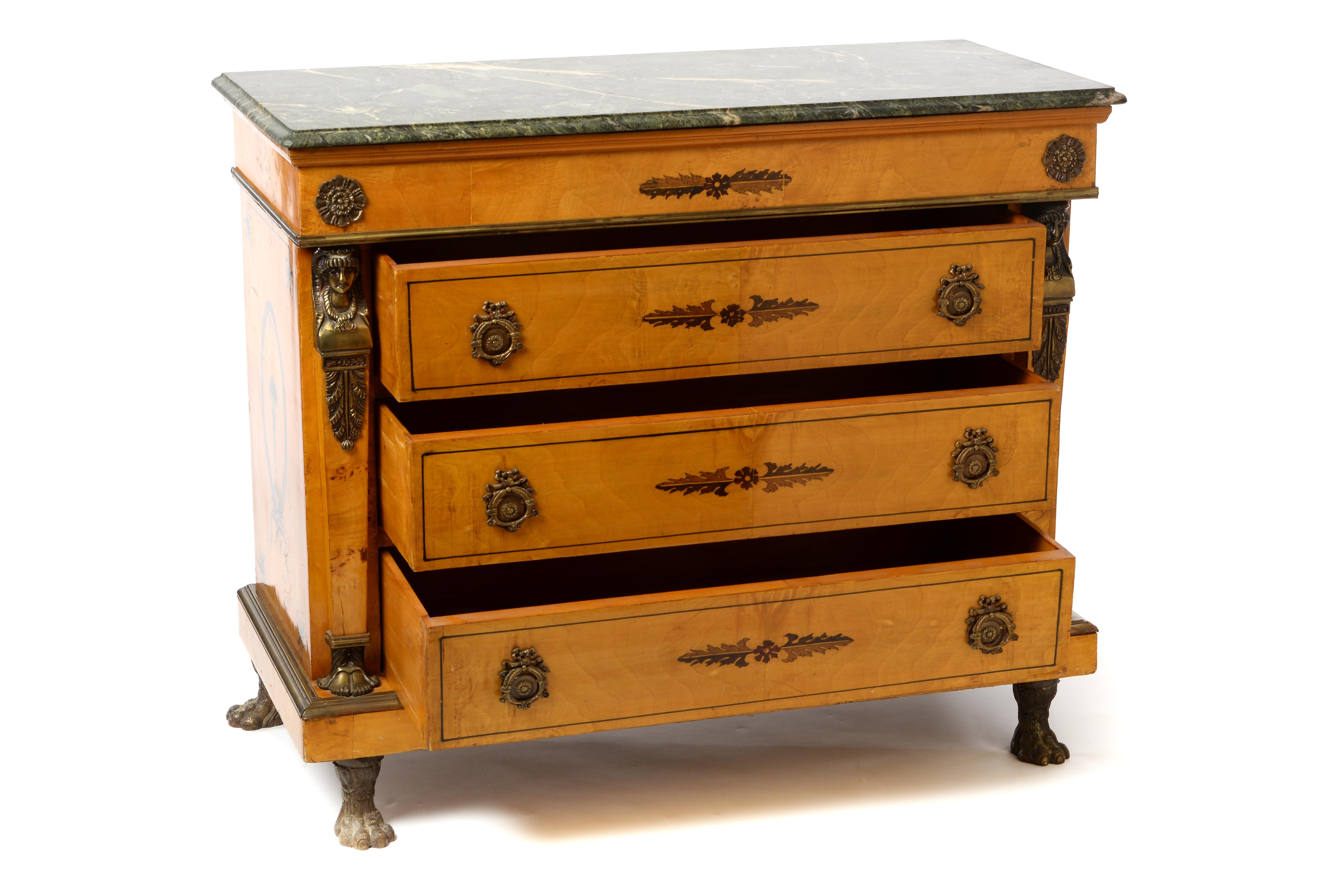 This beautiful honey colored Empire chest of drawers features unique brass applications, heavy paw feet, an impressive green marble top, and decorative floral marquetry - all of which contribute to the interesting appearance of this piece. This