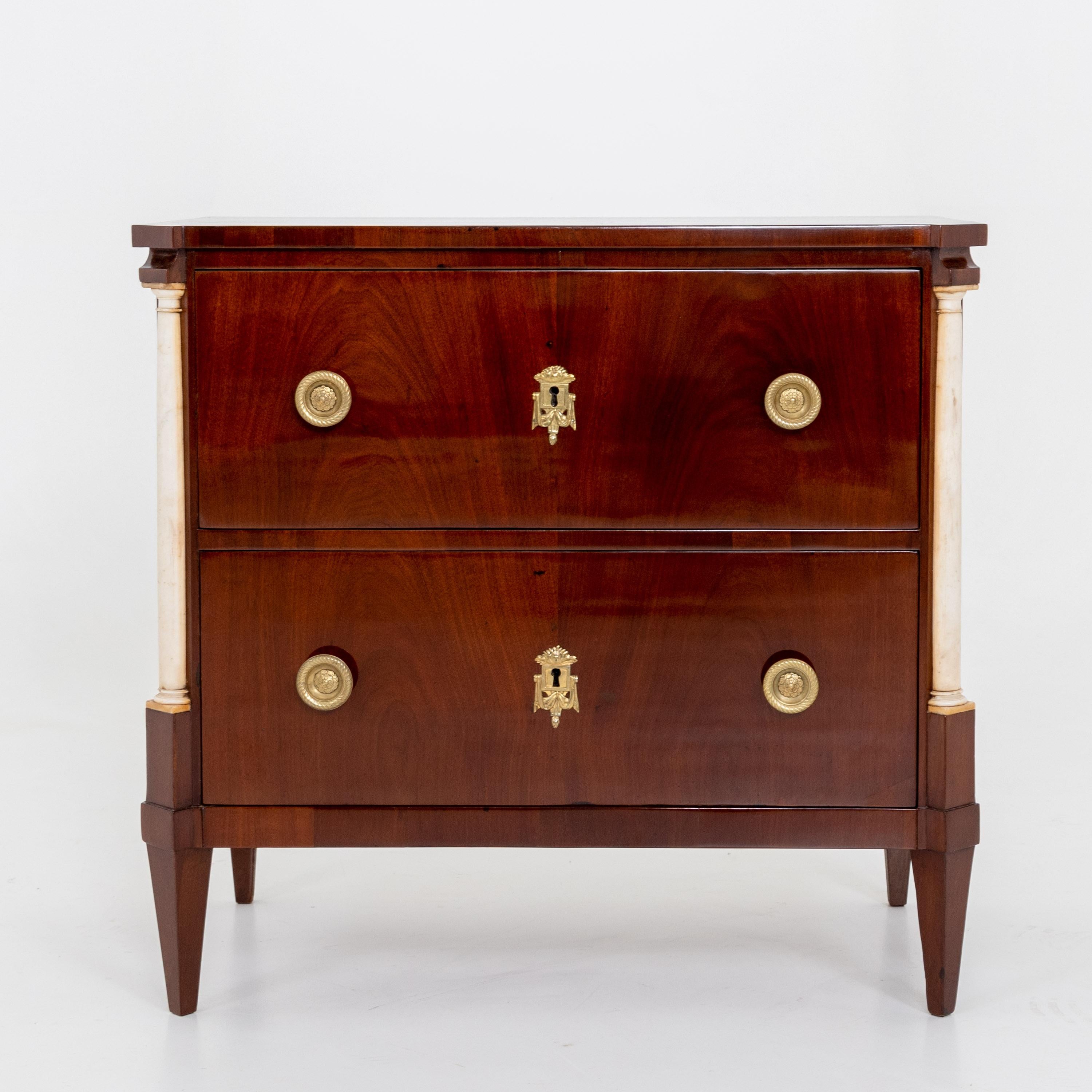 Empire chest of drawers with two drawers and quarter columns made of marble. The body is veneered in mahogany, the fittings are made of brass.