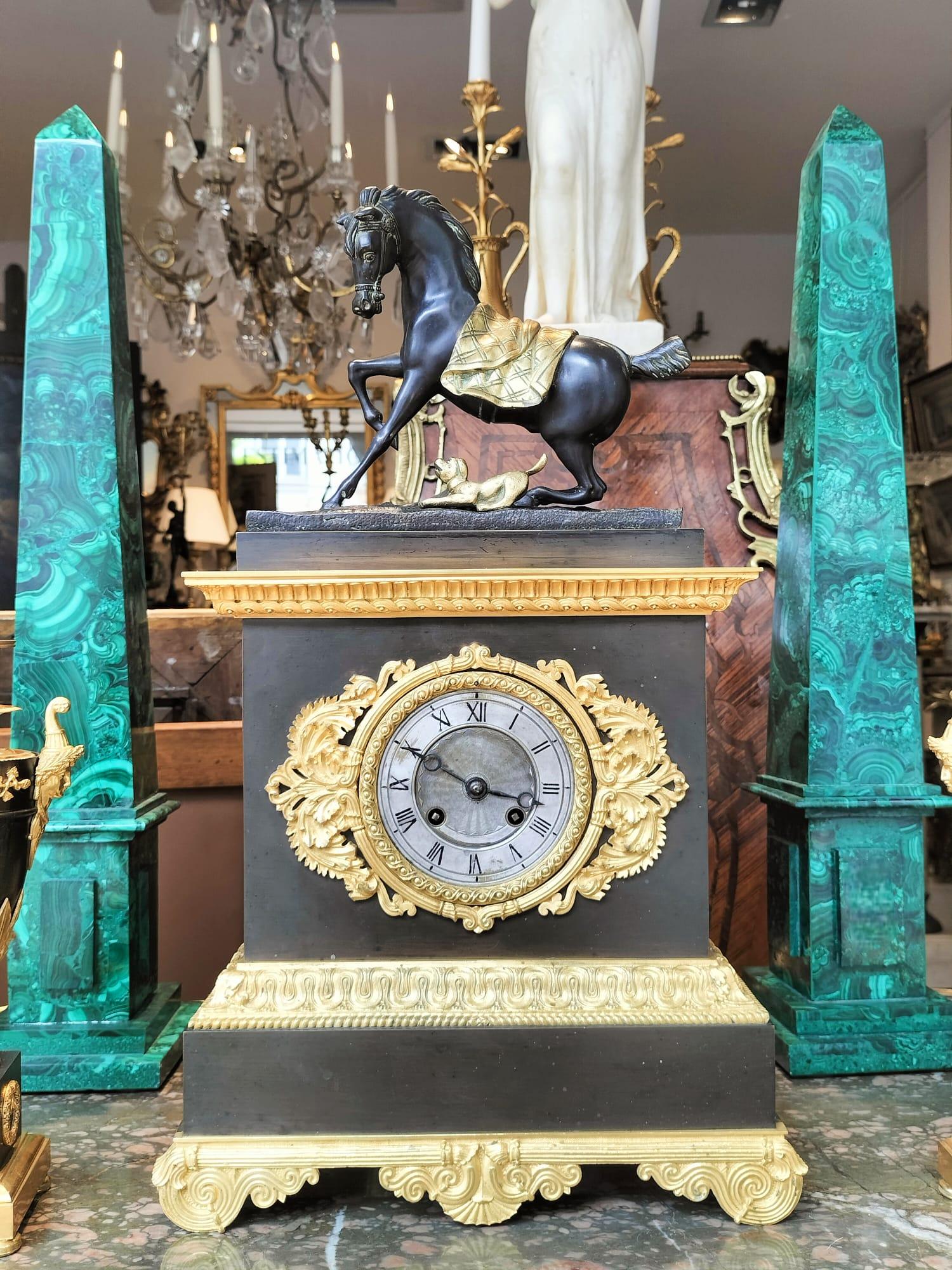 Restoration-period bronze clock with brown and gilded patina depicting a horse playing with a small dog.

Beautiful mercury gilding, the alternating patinas give a nice balance to the whole, as does the work on the details of the horse's head and
