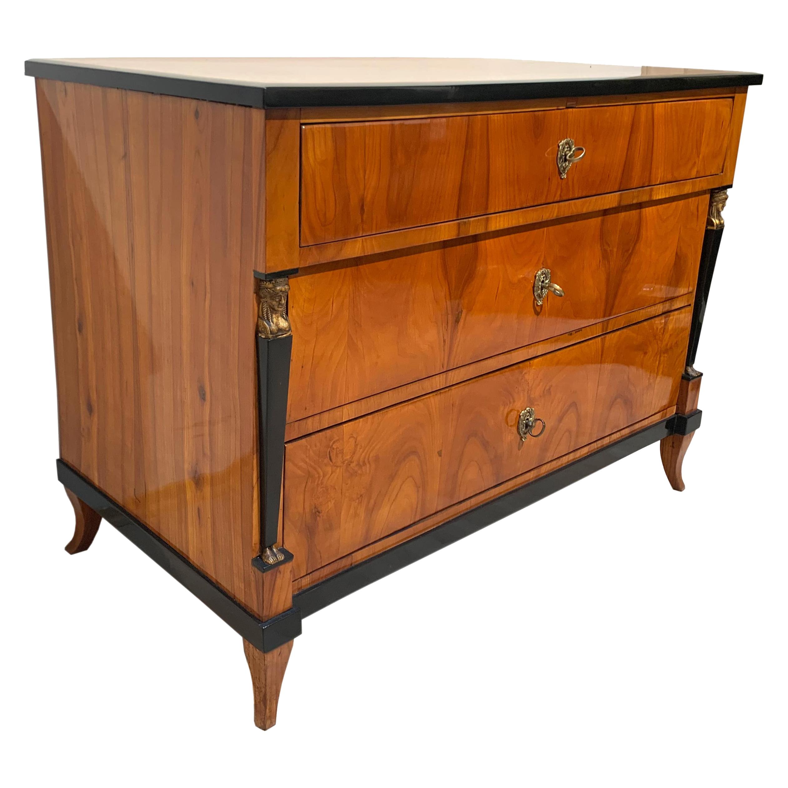Very fine, original and greatly restored neoclassical Empire Commode / Chest of three Drawers with beautiful caryatids from South Germany, circa 1810-1815.
Wonderful, bright and friendly cherry veneer and solid wood, book-matched and running over