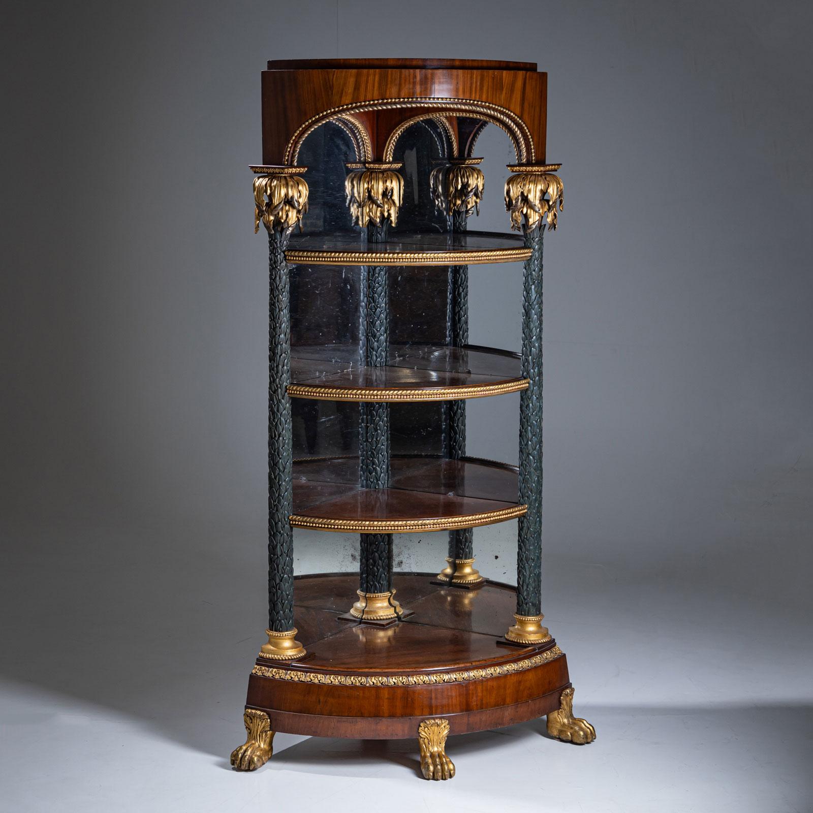 Excepcional étagère esquinera de caoba, apoyada sobre tres patas patinadas y patinadas en oro. La estructura en forma de segmento se apoya en tres estilizadas columnas en forma de palma, con bases patinadas en oro, fustes patinados en verde y