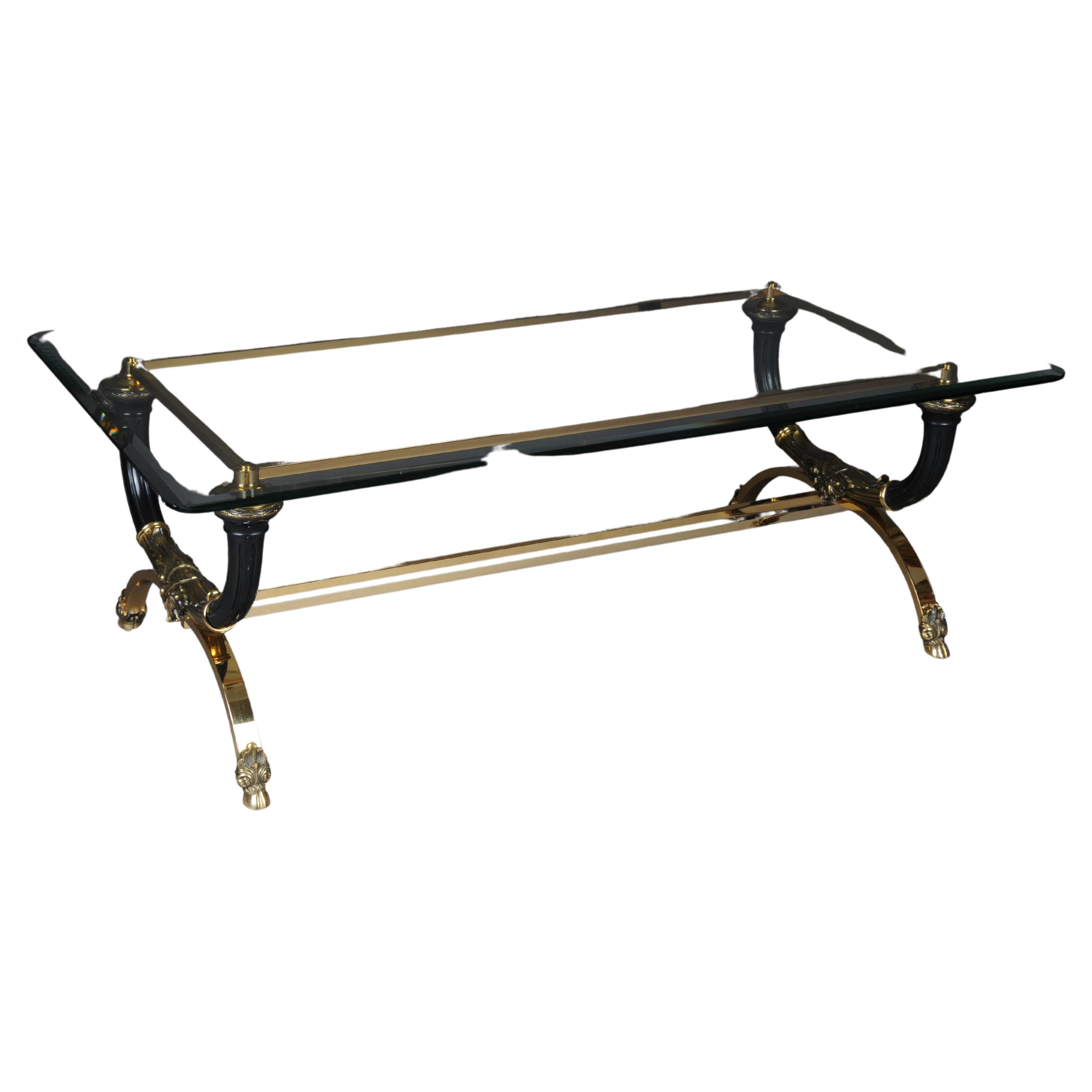 Empire designer coffee table, gold plated brass

high quality coffee table made of polished brass in neoclassical style. Symmetrically curved legs connected with a double-rowed center bar. Legs ending in hooves. Above black grooved cornucopiae.