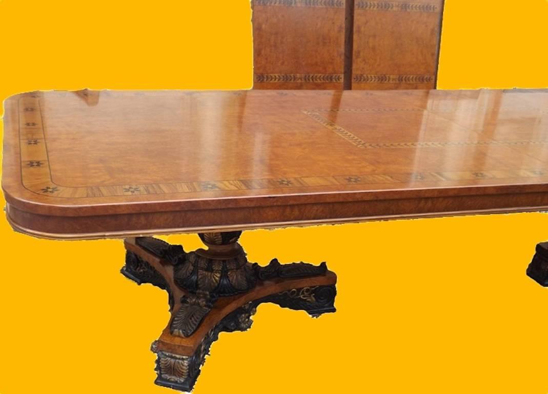 Superb inlaid twin pillar Empire style dining table, circa 1920 in walnut with exotic wood inlay and having gilded and hand-carved pedestal supports. This stunning table will seat 16 with ease and is nearly 5 feet wide which allows ample room for