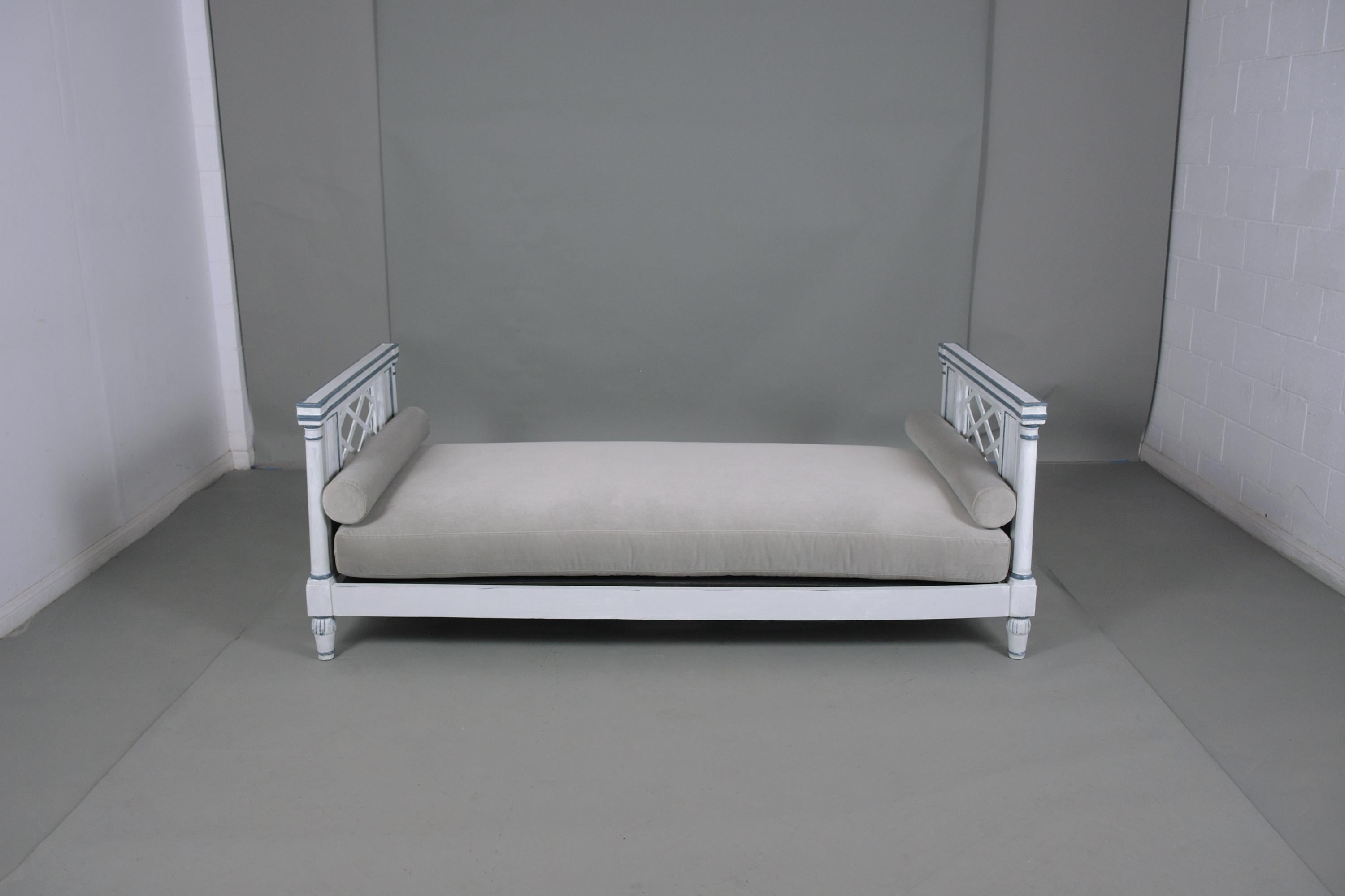 An extraordinary antique empire daybed is hand-crafted out of walnut and newly restored finished and upholstered by our professional craftsman team. This comfortable daybed has been newly painted in an oyster color & is accentuated with navy blue