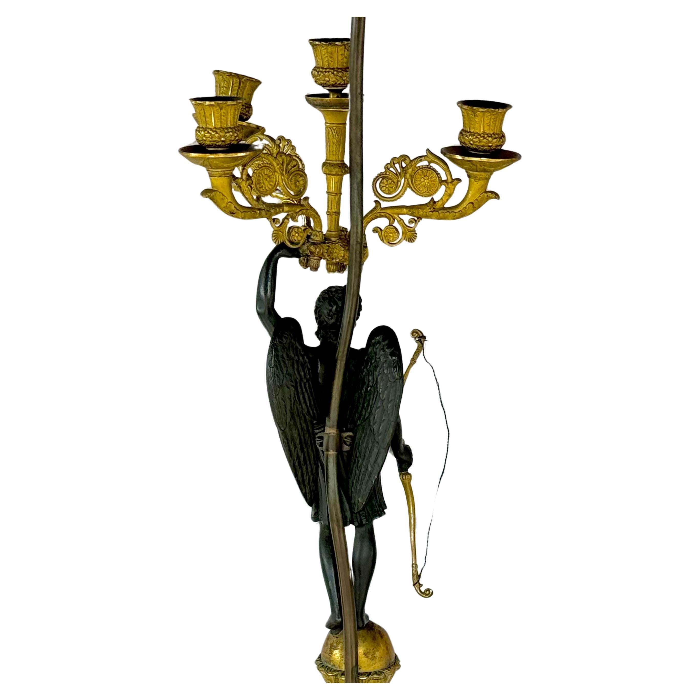 Candelabro de bronce y patinado del siglo XIX montado como lámpara. La lámpara incluye una preciosa estatua patinada de Diana la Cazadora con alas y arco de arquero. Sobre la mano izquierda de Diana hay un candelabro dorado que tiene cuatro ramas