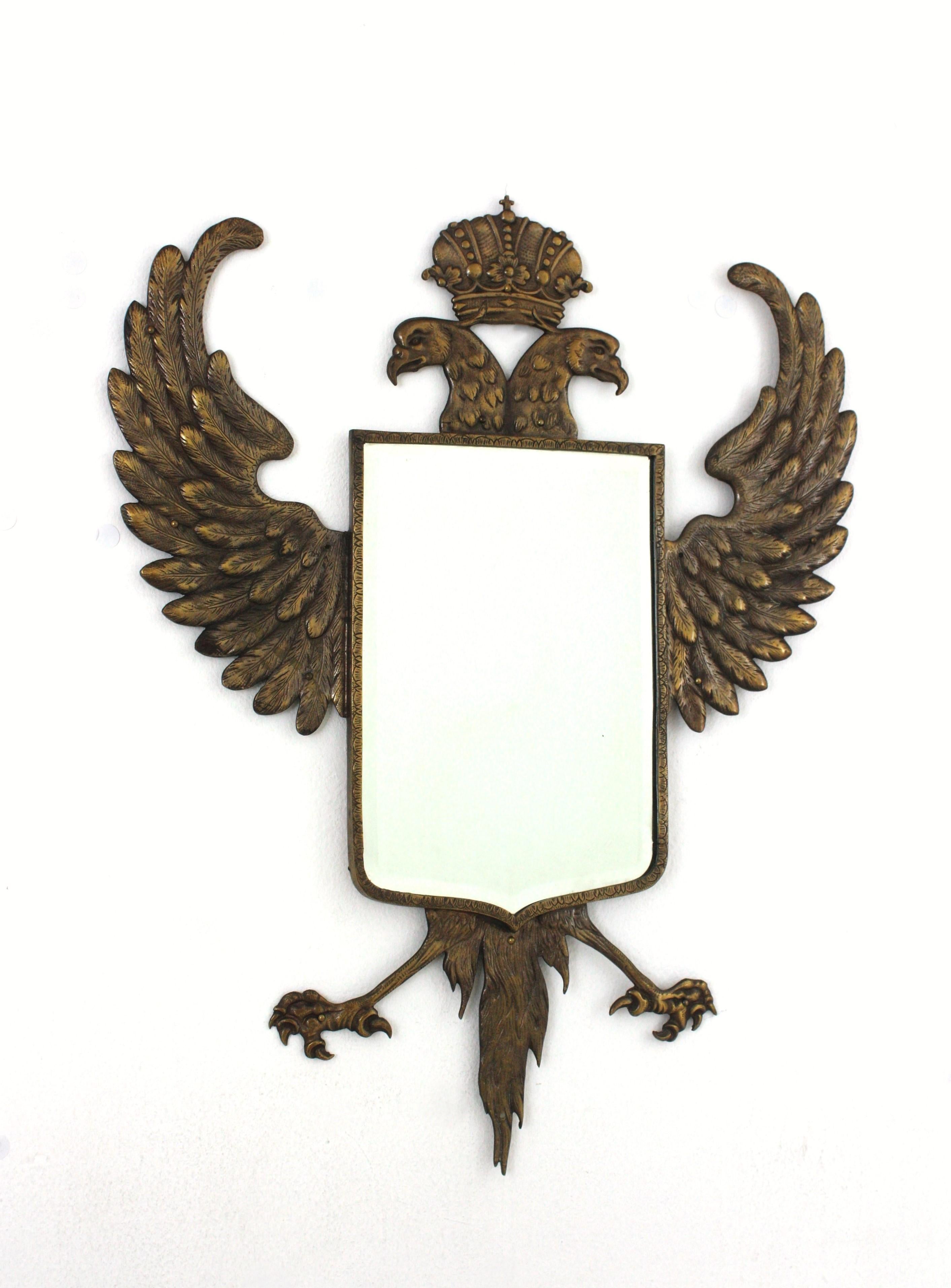 Two Headed Eagle Bronze Wall Mirror, Spain, 1930s-1940s.
Spectacular bronze wall mirror with a crowned double headed eagle surrounding a shield shaped beveled glass.
This bronze mirror features a double headed eagle with wide open wings and a crown