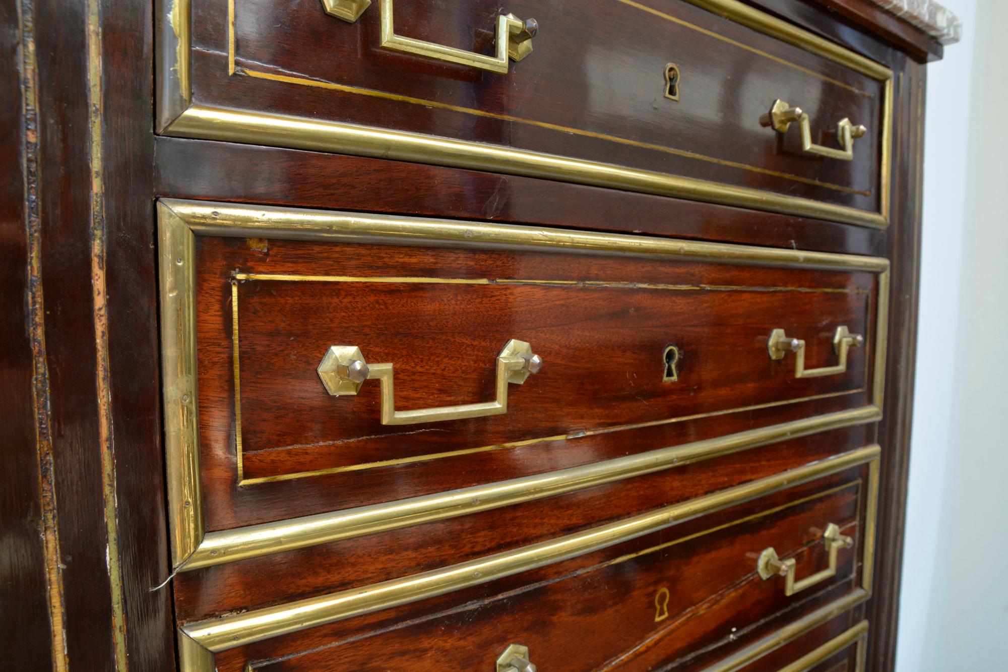 Empire dresser or secretary, Paris, 1810s. Made of mahogany.

Feet with fine brass applications. Eight drawers with fine, circumferential brass strips, two handles each, key inlays also in brass, original marble top. Lateral pilaster strips each