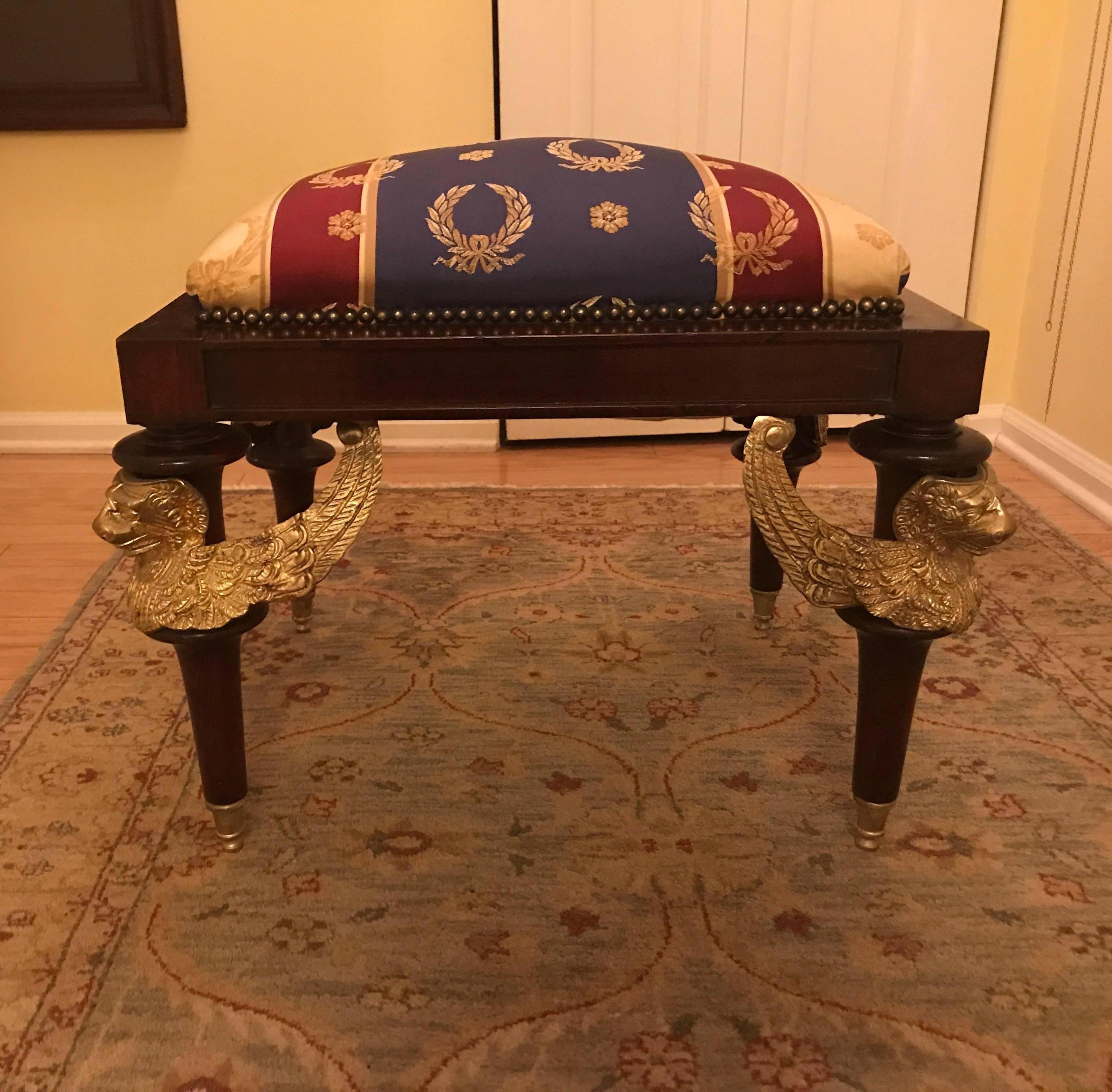 Opulent Egyptian revival gilt mounted bench. The rectangular bench with four trumpet legs with winged figurative Egyptian style mounts resting on four gilt capped feet. The fabric is jewel tone Napoleonic silk.
