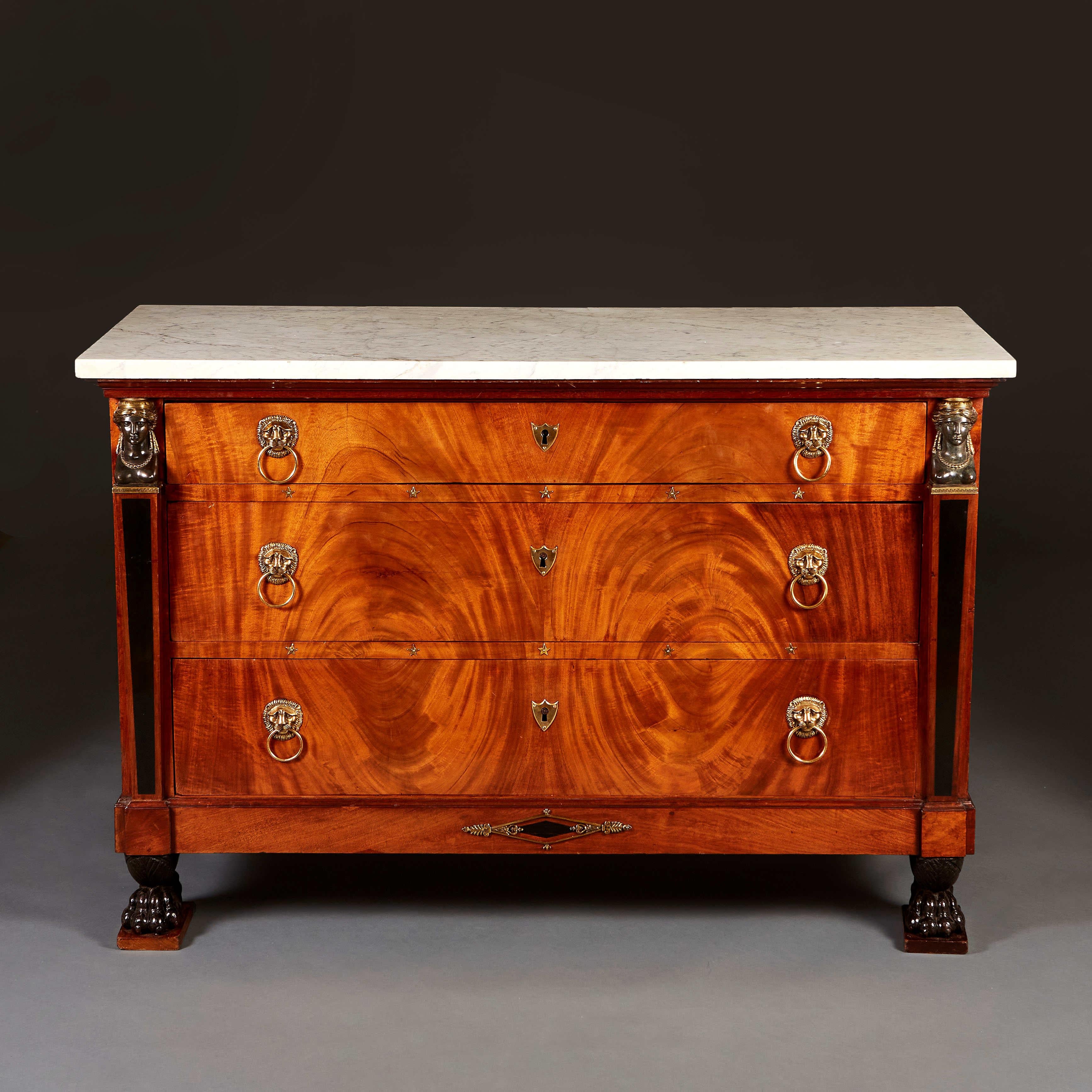 Belle commode Empire du début du XIXe siècle en acajou flammé, avec trois tiroirs gradués à l'avant, avec des poignées en forme de masque de lion dorées au feu, des étoiles décoratives bordant les tiroirs, les montants surmontés de cariatides