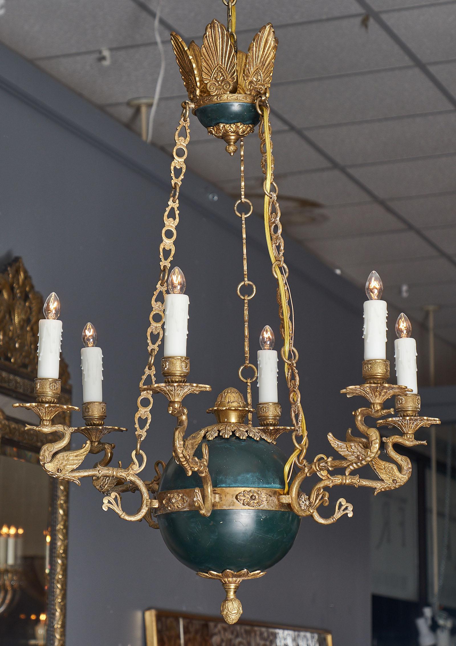 A fine French Empire swan chandelier featuring six branches of finely cast gilded bronze shaped as swans. The rich bronze decor of acorns and acanthus is found throughout. The center body of the chandelier is made of tole. This chandelier has been