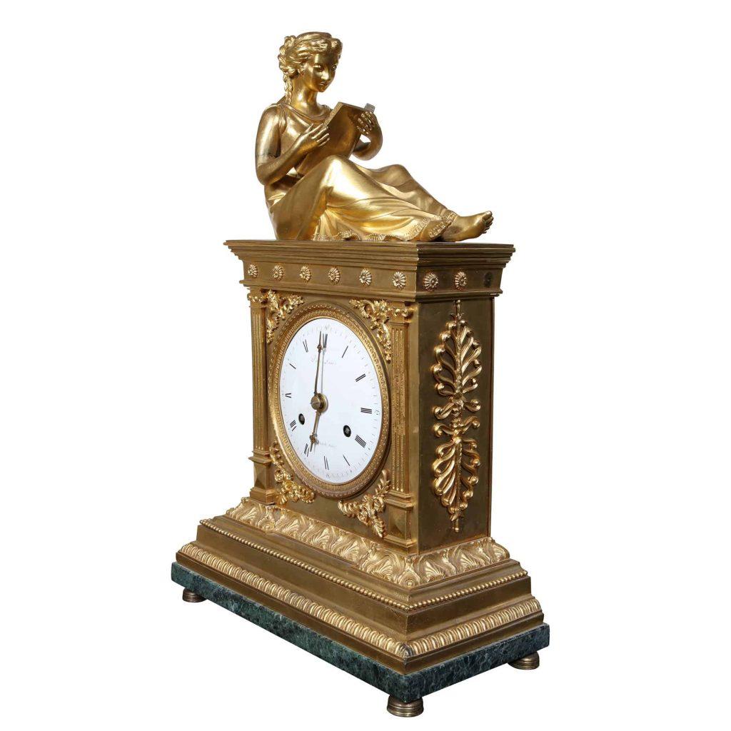 A fine early 19th century fire gilt French mantle clock circa 1810, with a reclined figure of learning reading a book above a white enamel dial, signed Dautel, Rue de Thionville à Paris. Fine enamel dial with Roman numerals and Arabic quarter