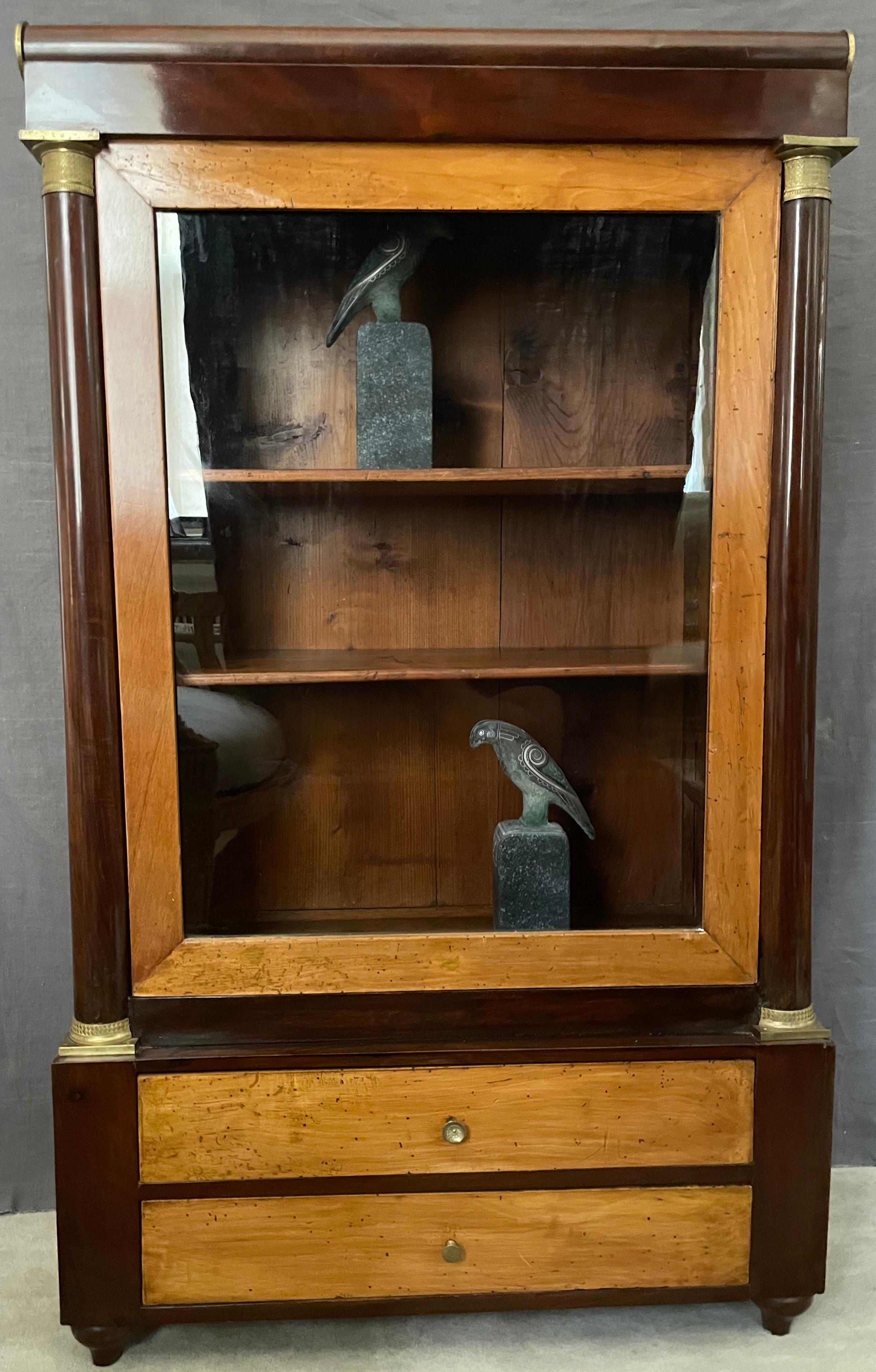 Empire guillotine cabinet. Fine Neoclassical fruitwood and mahogany vitrine small bookcase cabinet with glass panel door àla guillotine above two drawers. An unusual late remiEmpire period cabinet with three interior adjustable shelves and a
