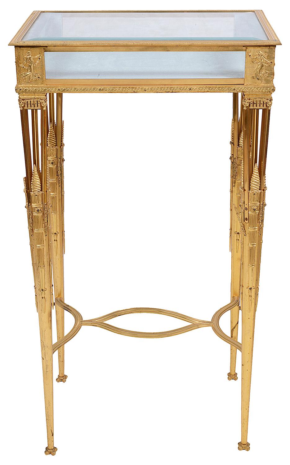 A very good quality late 19th century gilded ormolu Empire influenced Bijouterie display table, having a hinged top opening to reveal a silk lined interior. Classical fingers mounted on the corners, pierced and motif decoration, raised on tapering