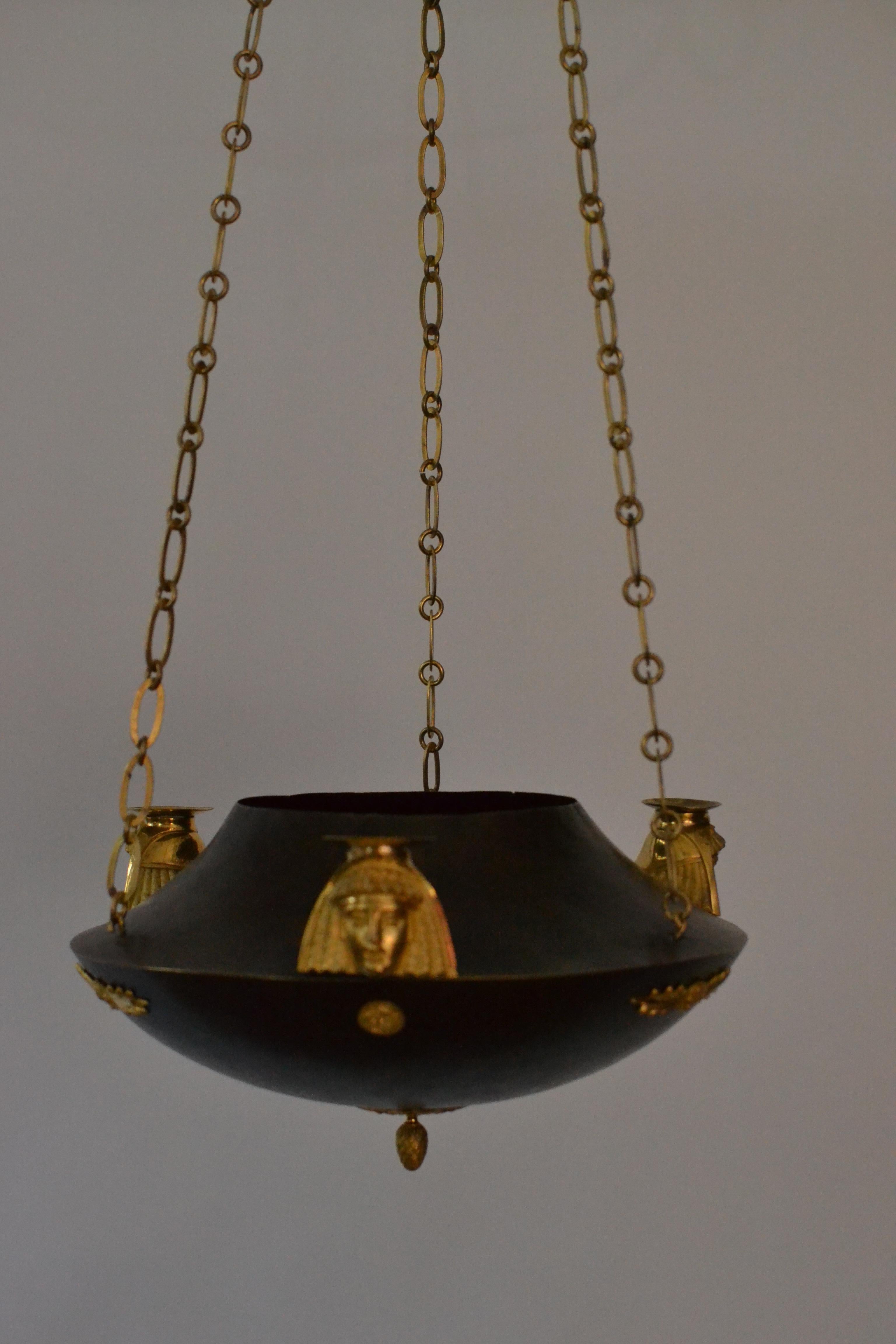 A Swedish empire lamp with three candleholders. The candleholders in the shape of Egyptian heads. Patinated copper and gilt bronze.