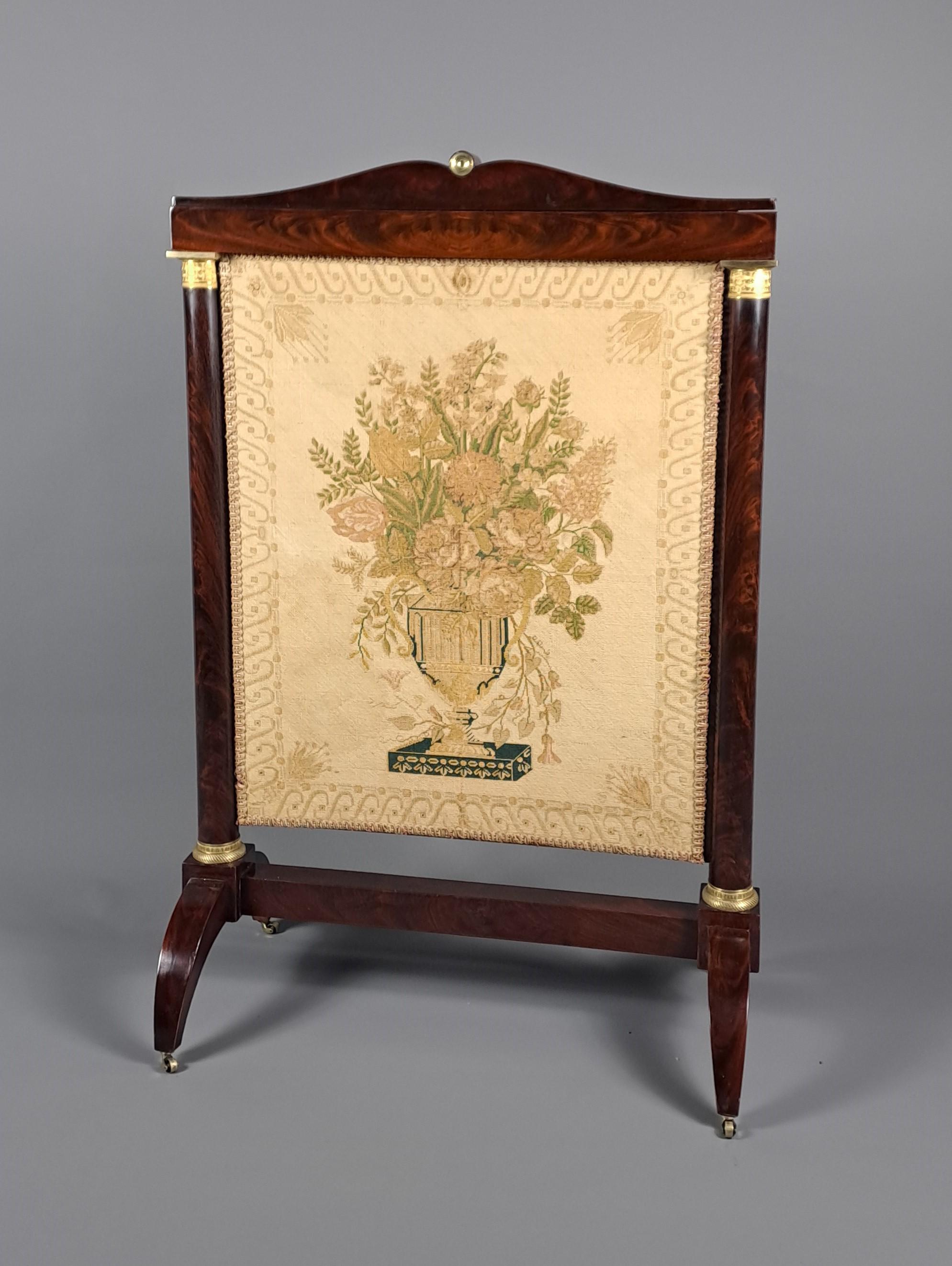 Large Empire period fireplace screen  in Mahogany and gilded bronze.

Front of the screen covered with a tapestry with small dots showing a flower vase, at the back an old silk with Empire patterns.

Ingenious weight system allowing the screen to be