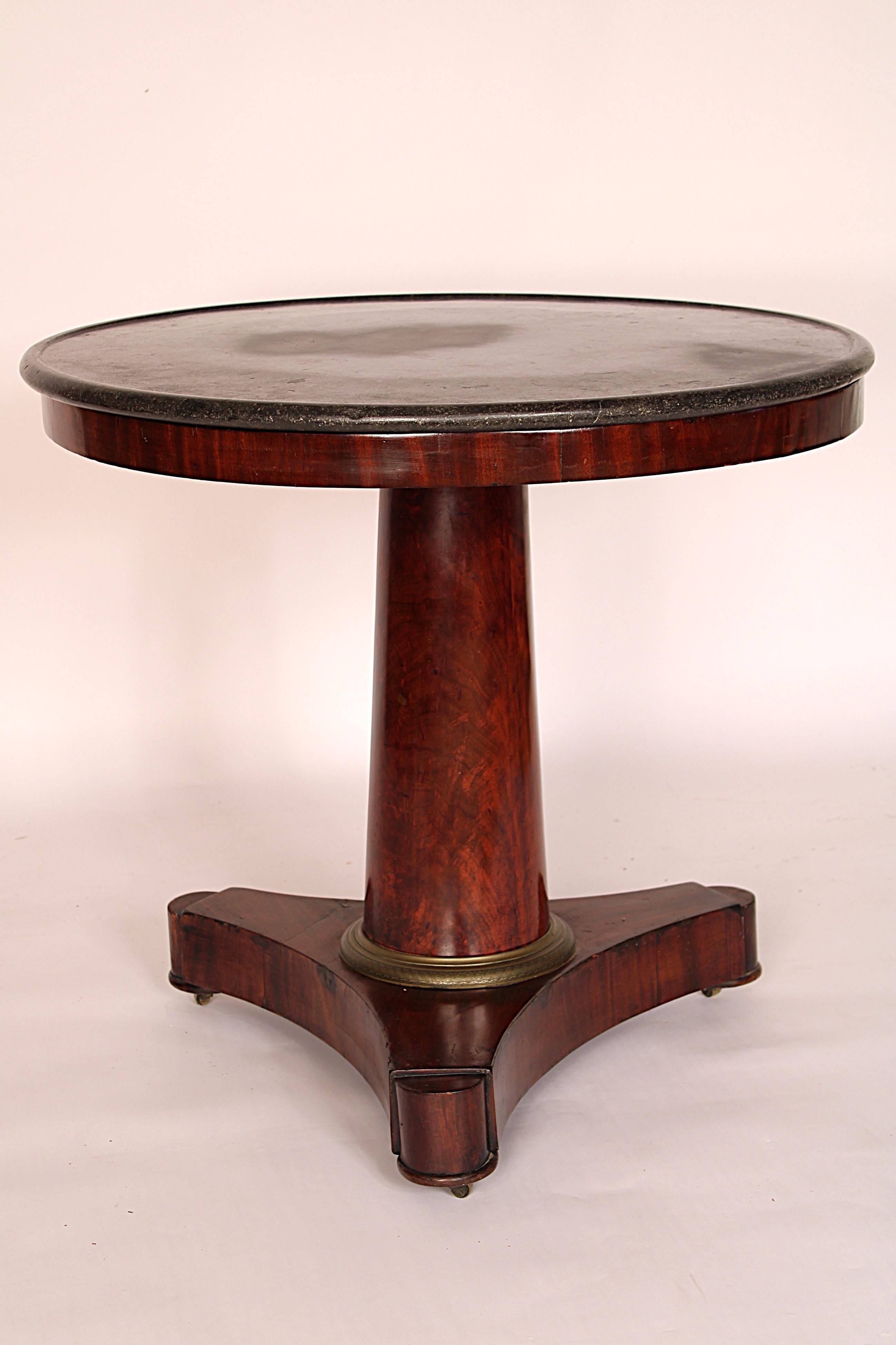 Period Empire mahogany center table with marble top, circa 1830. With a round marble top with molded edge, a flame mahogany pedestal with an ormolu ring at the base resting on a platform base with 3 extensions.