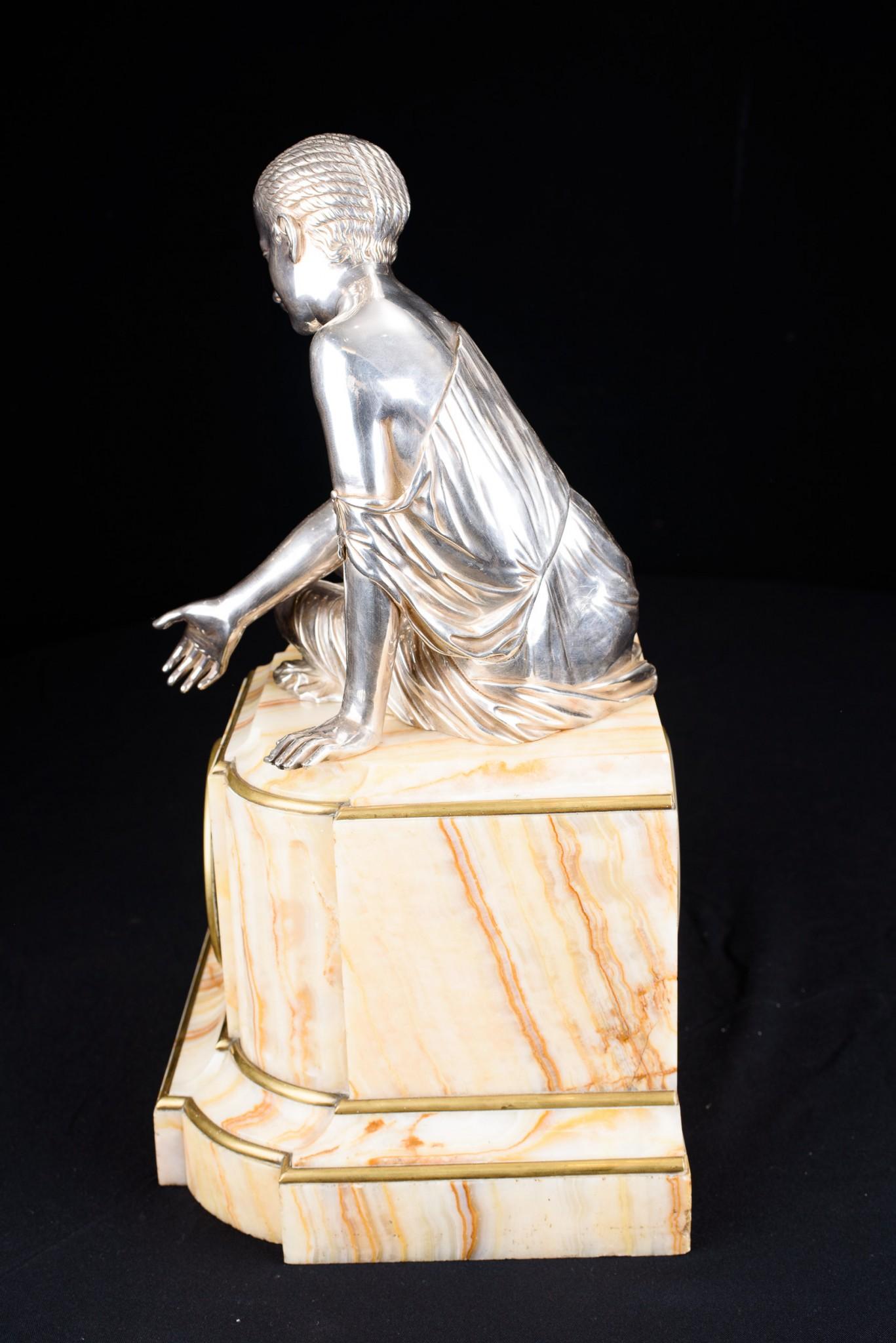 - Auffällige Manteluhr im französischen Empire-Stil - Onyxsockel mit bronzener, versilberter Frauenfigur auf der Oberseite - Wir datieren dieses außergewöhnliche Zeitstück auf ca. 1920.