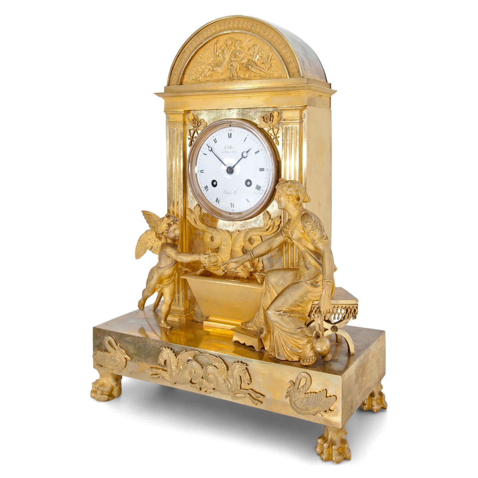 Large mantel clock in a gilt bronze case with an enamel clock face with Roman hours and Arabic minutes. Labeled Gallé, Rue Vivienne à Paris and Thomas. On the rectangular plinth is a figurative depiction of the sitting Venus with Amor, reaching