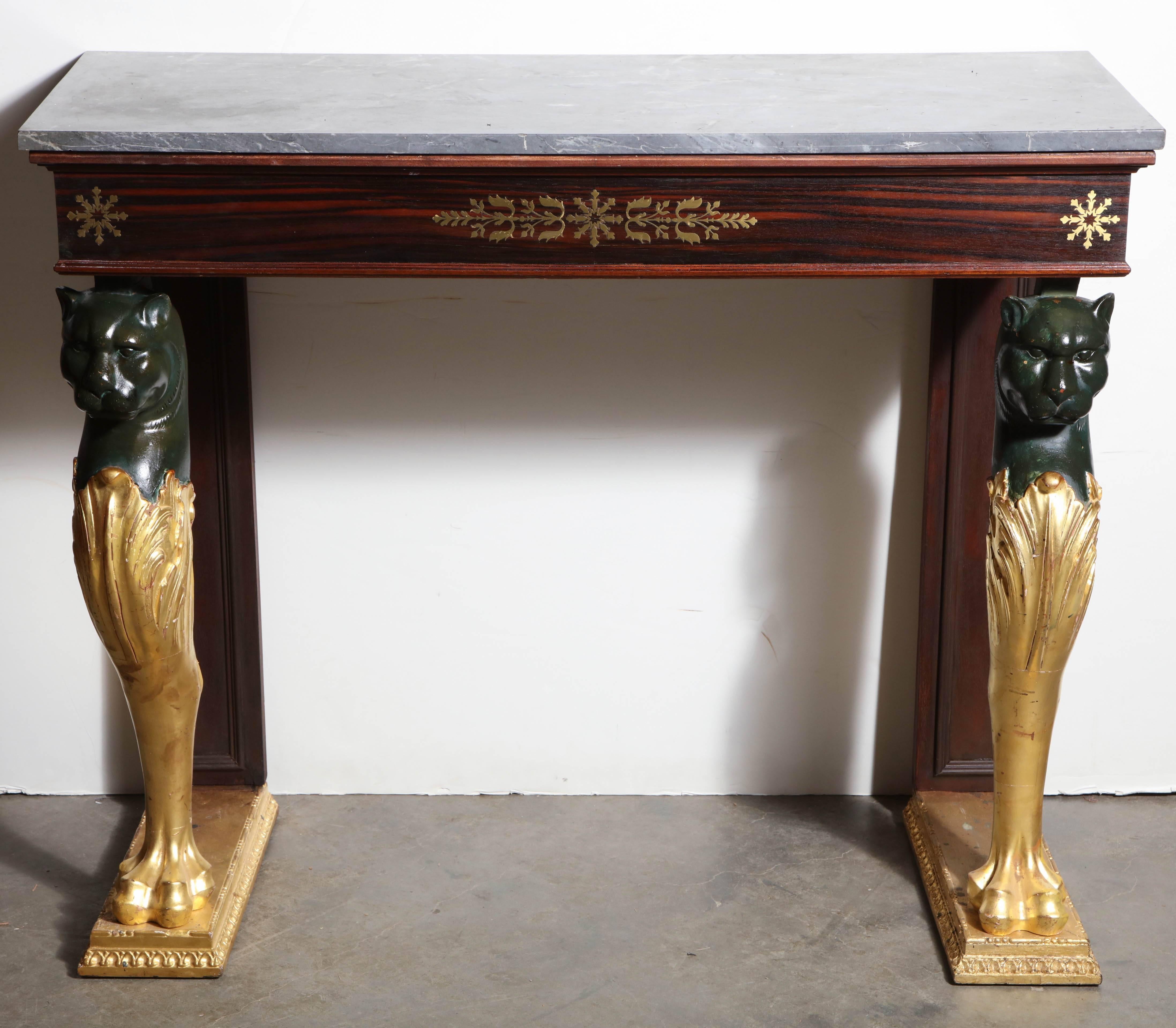 French Empire marble-top console pier table with rosewood and brass inlaid apron and gilded and painted lion form legs.